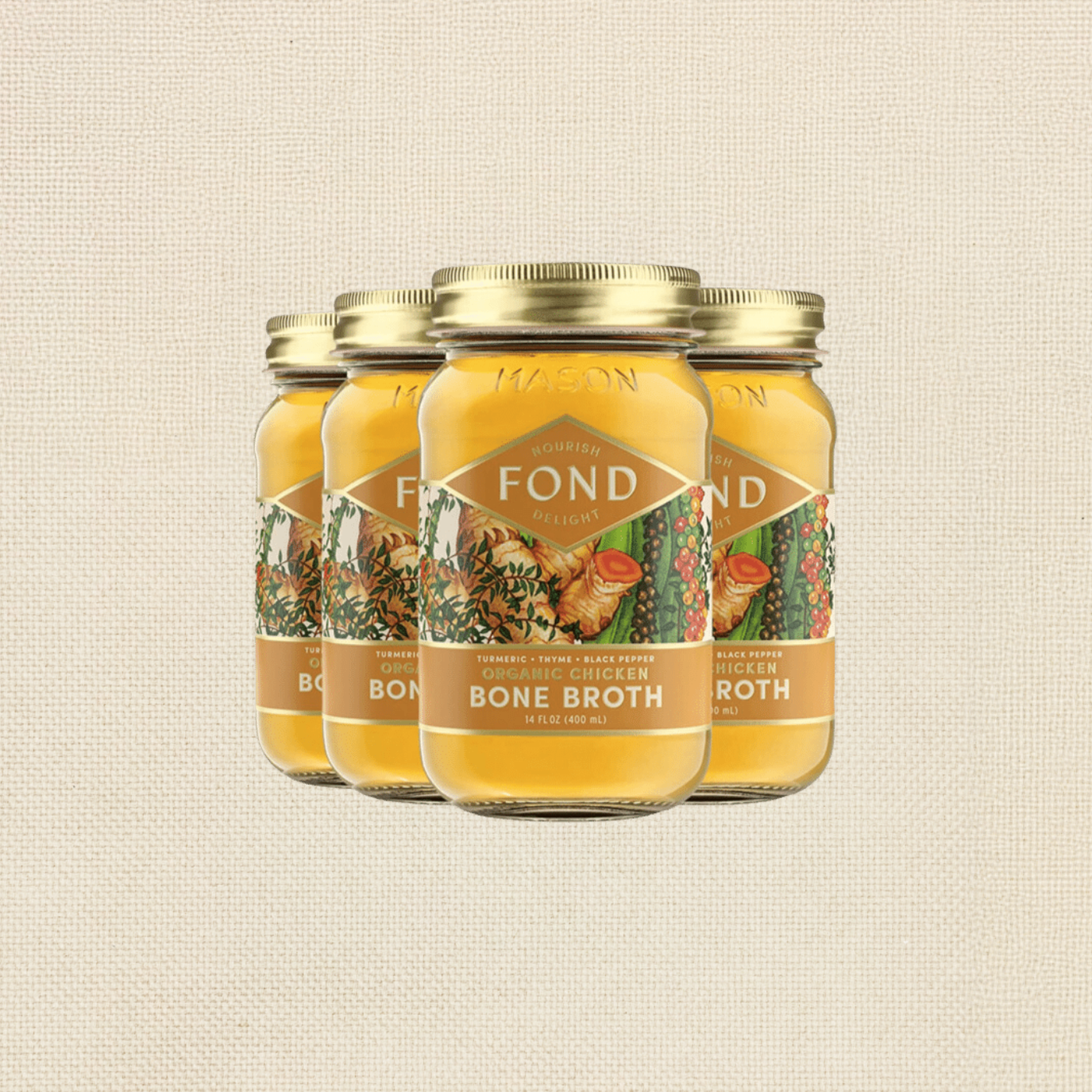 Four jars of FOND organic chicken bone broth with turmeric, thyme, and black pepper on a beige textured background.