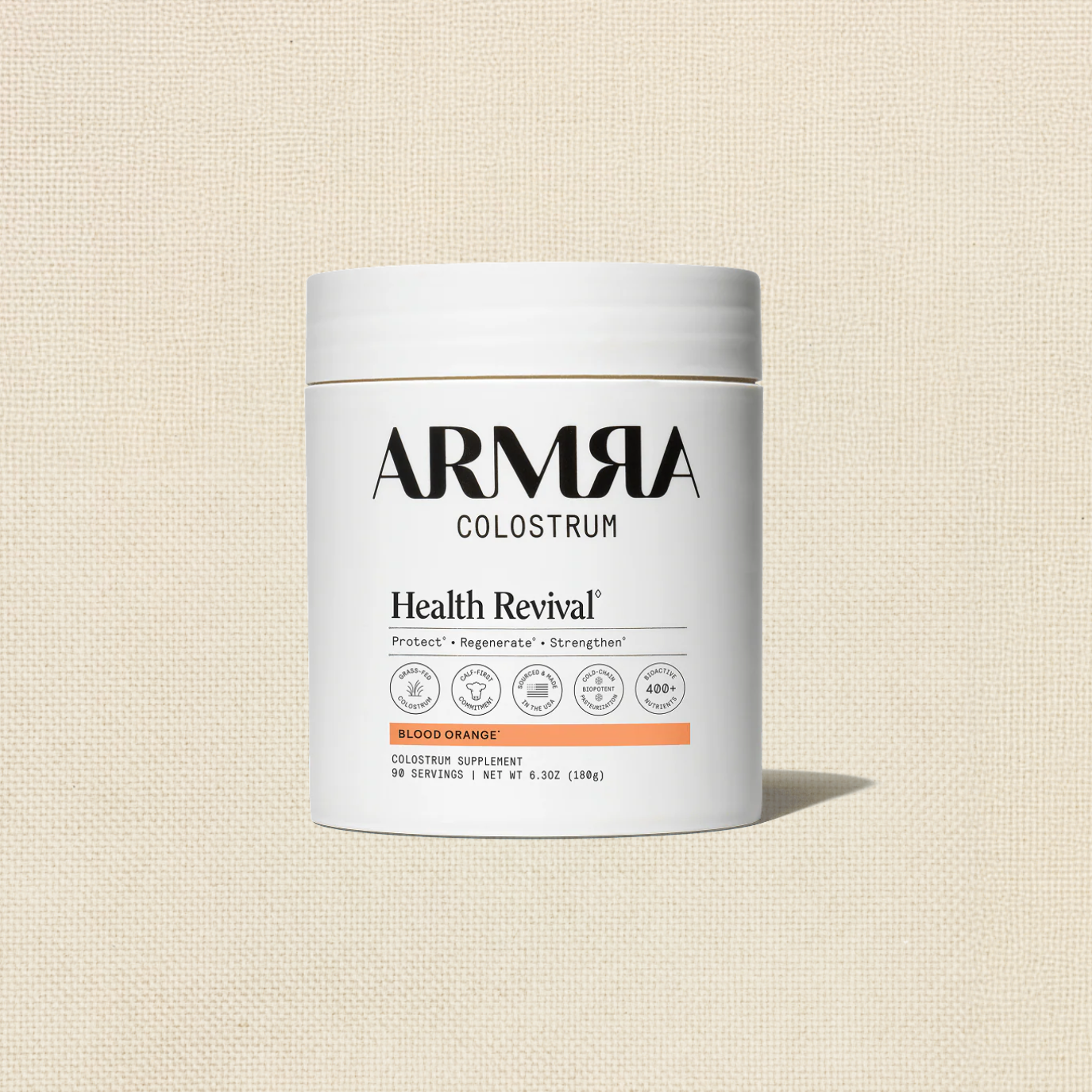 A white container of Armor Colostrum Health Revival supplement on a beige textured background with the label visible.