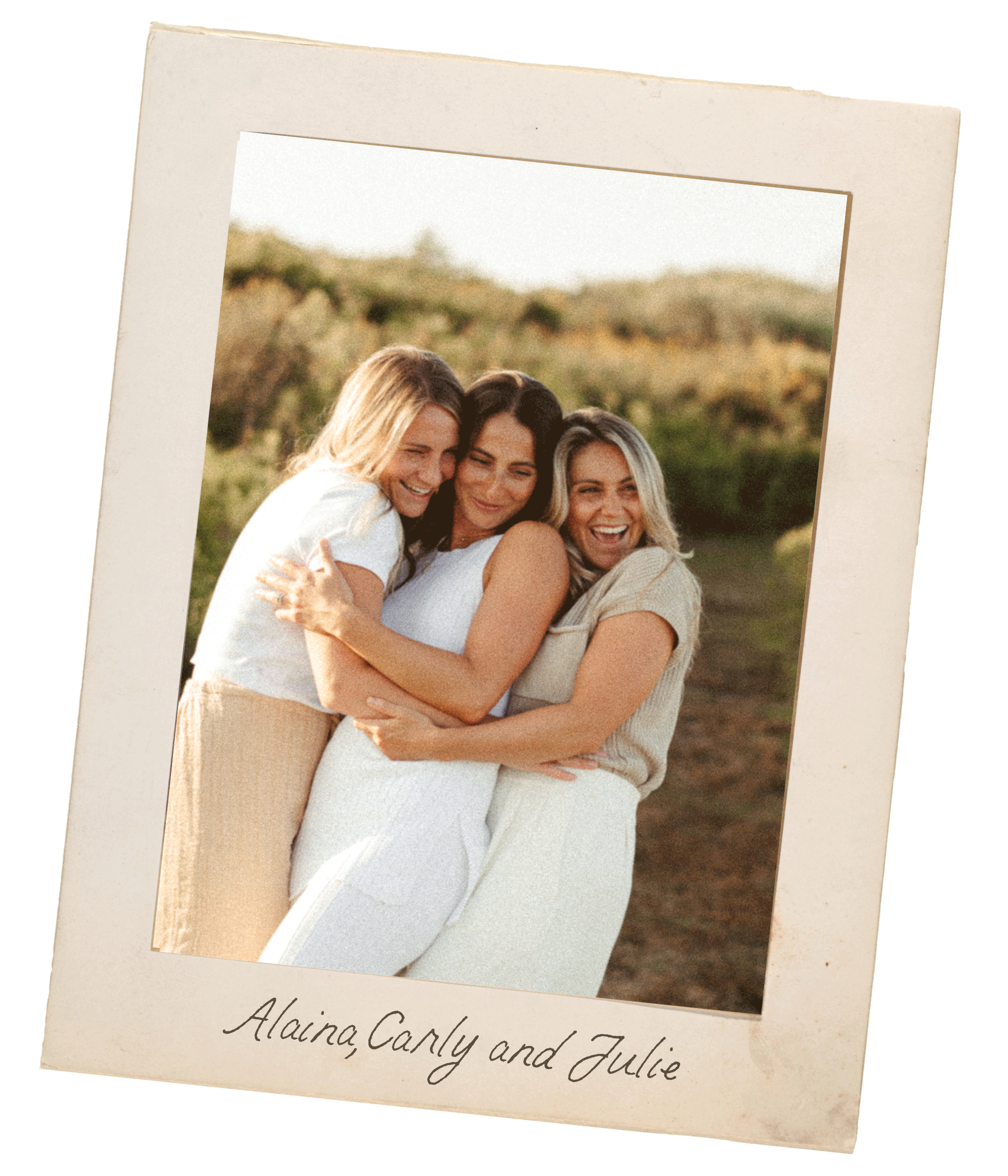 Three women hugging and smiling outdoors with a blurred natural background.