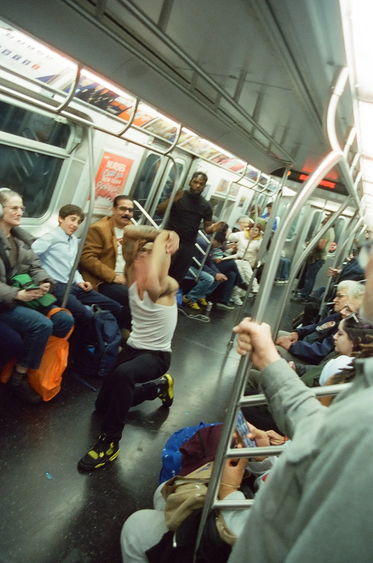 A woman performing a dance in the middle of a crowded subway car with seated and standing passengers watching.
