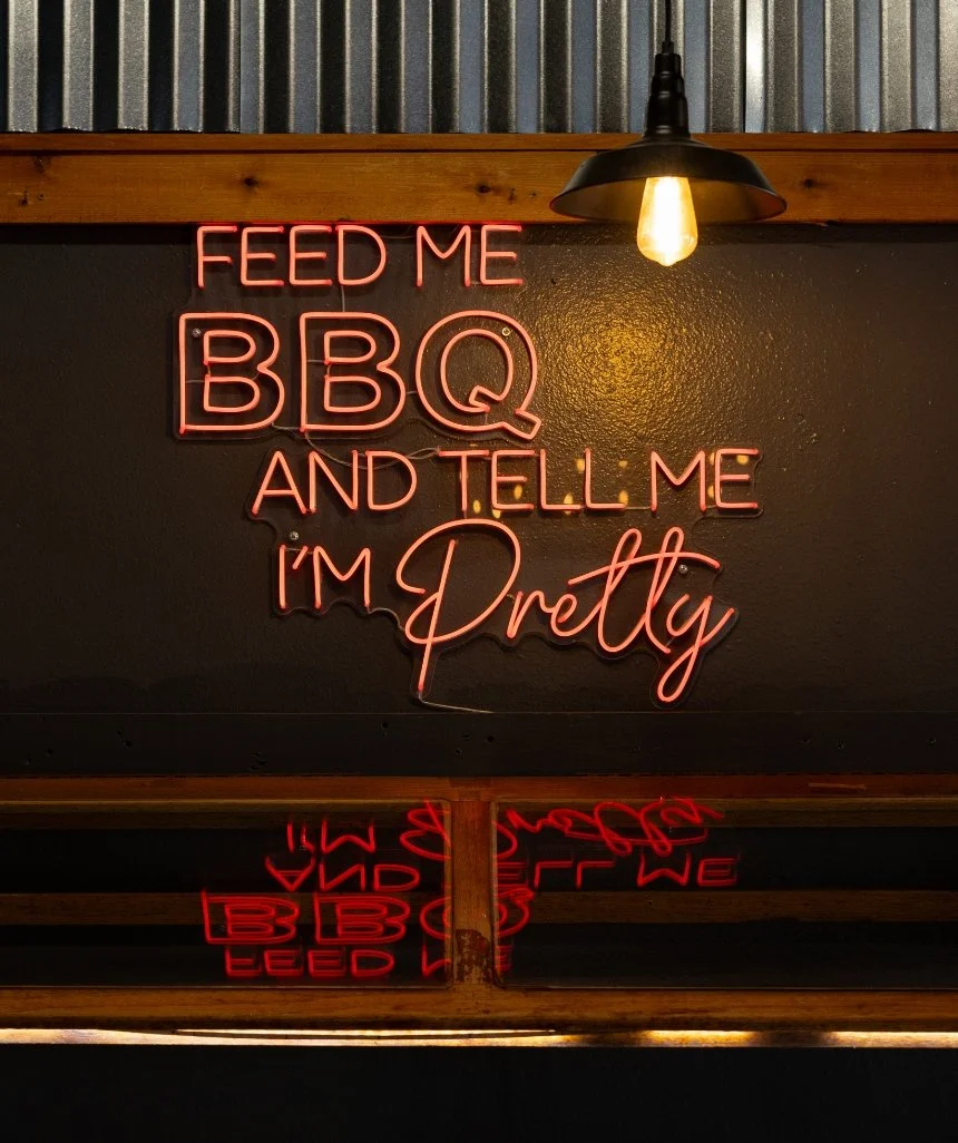 Neon restaurant sign reading ‘Feed Me BBQ and Tell Me I’m Pretty.’