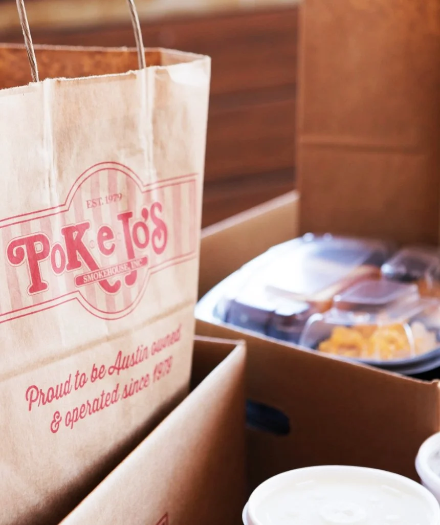 Pok-E-Jo’s to-go boxes and branded bags arranged on a counter.