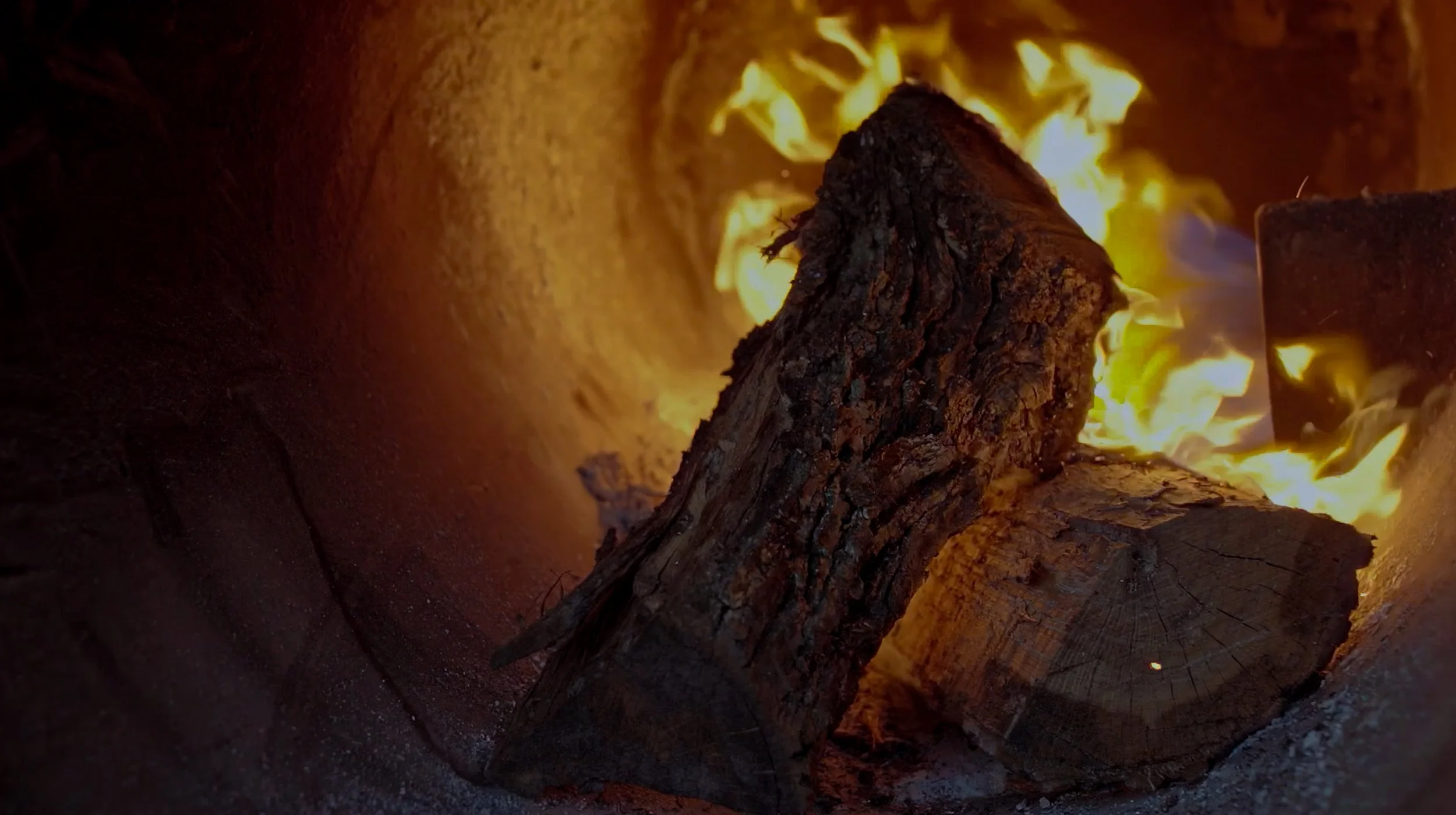 Inside of fire pit with logs and flames.