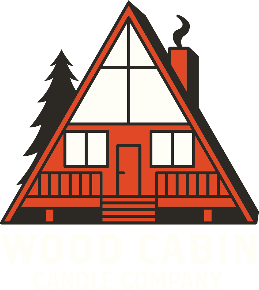 Logo for Wood Cabin Candle Company featuring a stylized A-frame wood cabin with a chimney and trees in the background, with text below reading 'WOOD CABIN CANDLE COMPANY'.
