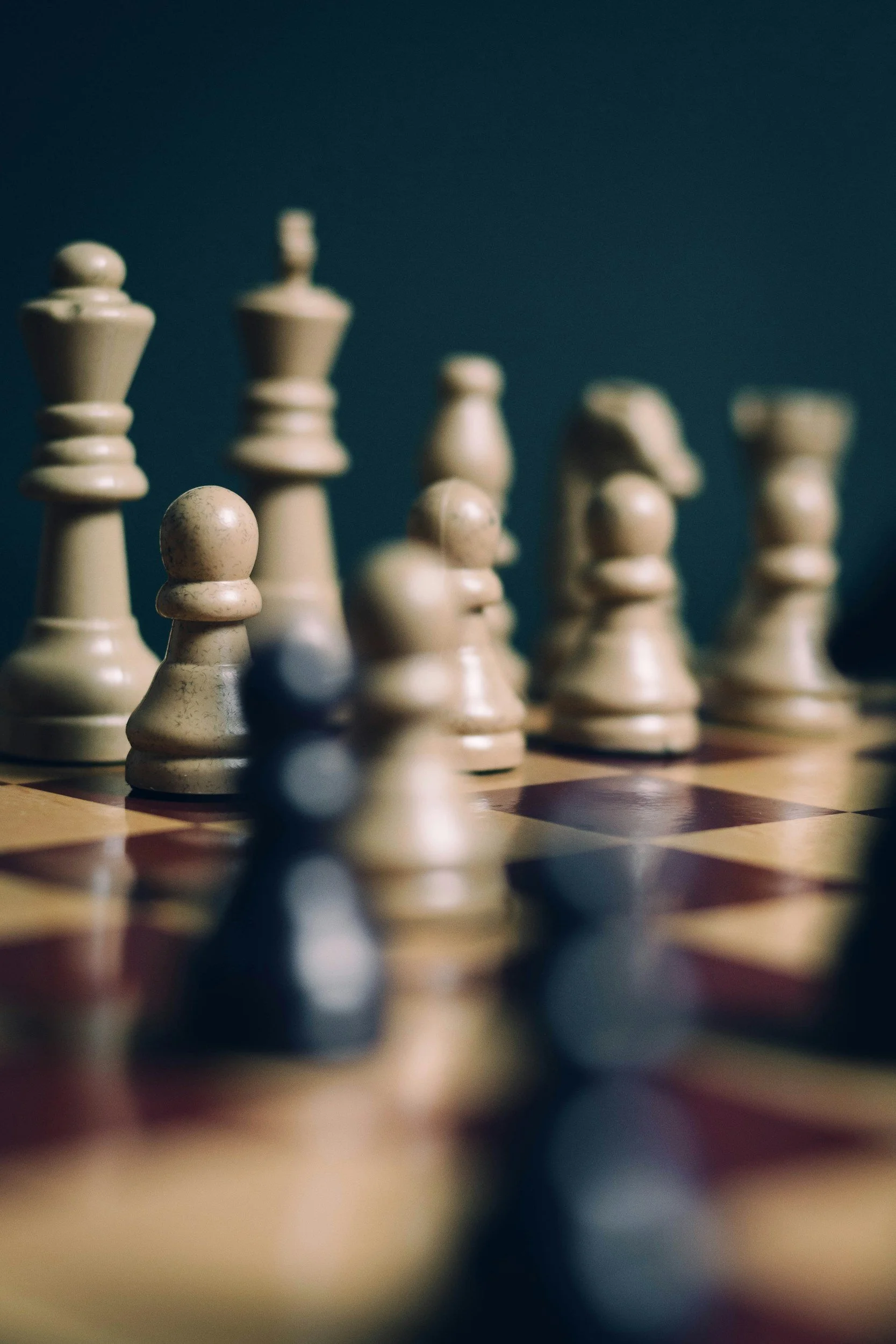 Close-up of a chessboard with several chess pieces, including rooks and pawns, placed on the squares, with a dark background.