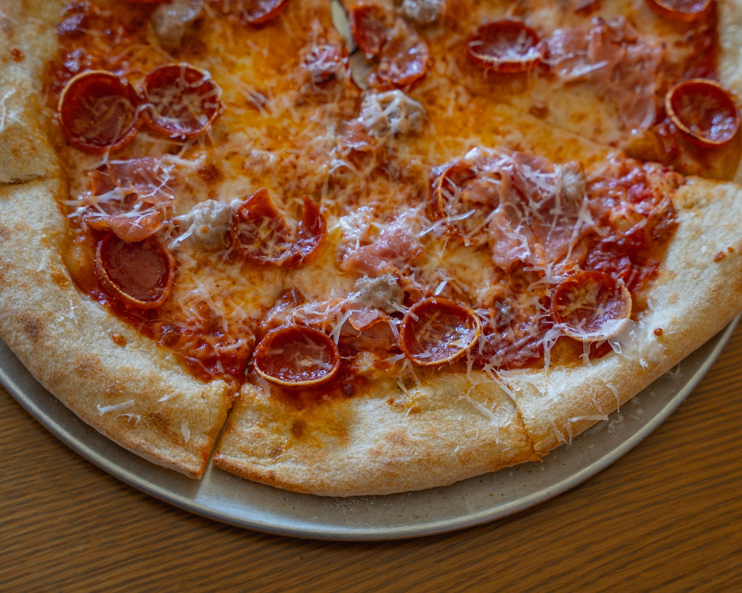 Close-up of a pepperoni and cheese pizza on a gray plate on a wooden table.