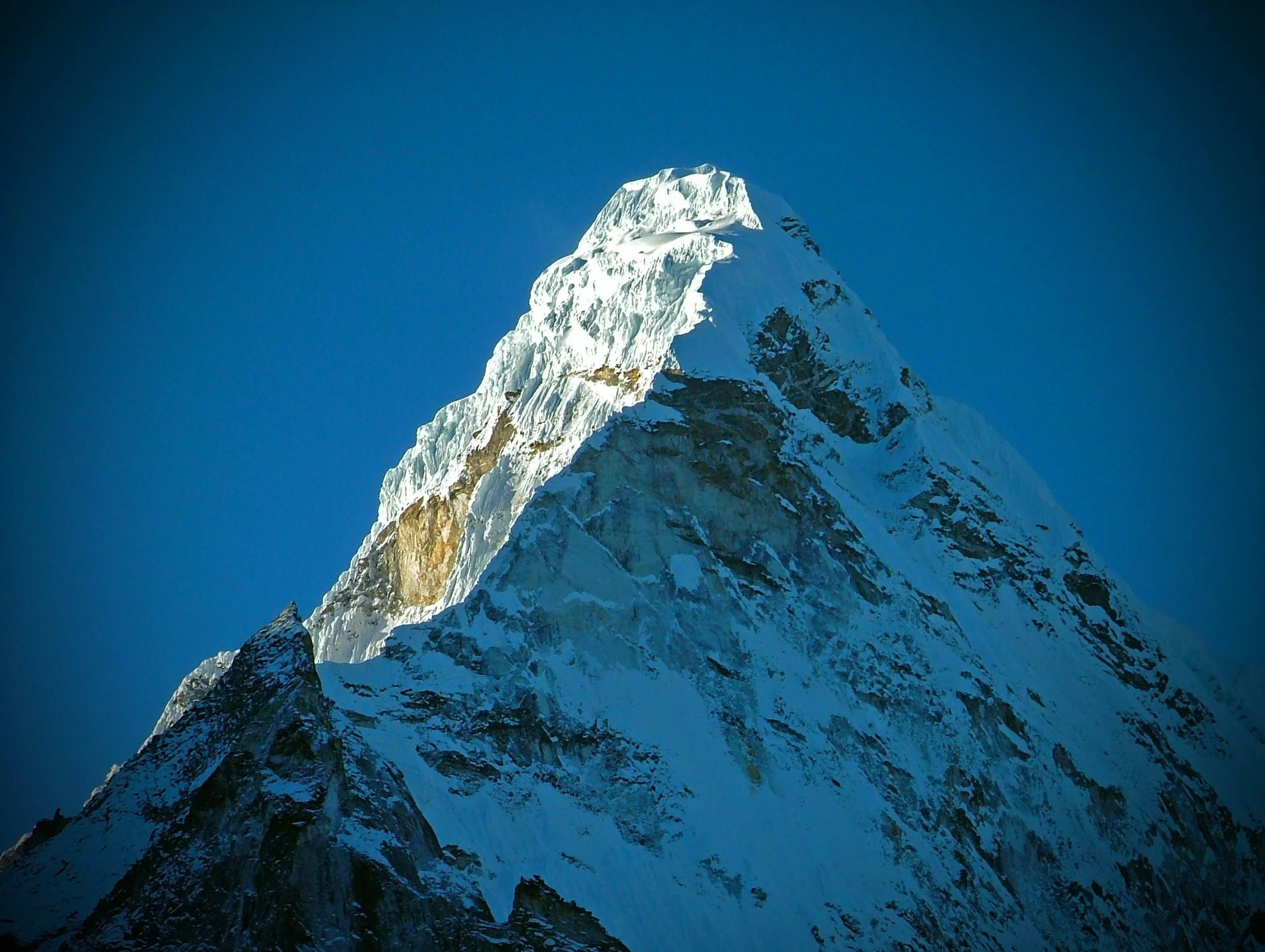 Snow-covered mountain peak against a clear blue sky.
