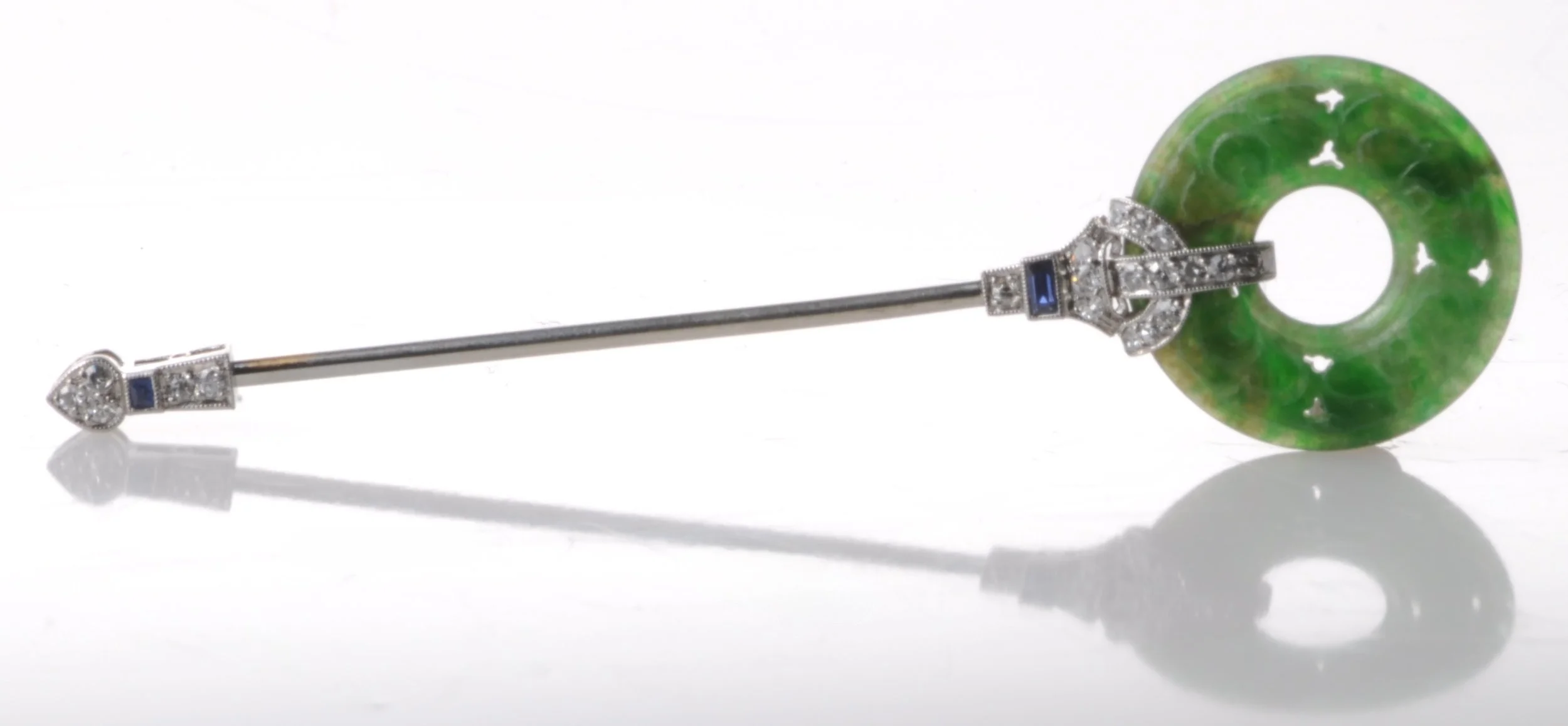 Art Deco jabot pin featuring a carved jade disc accepted with diamonds and sapphires set in platinum.