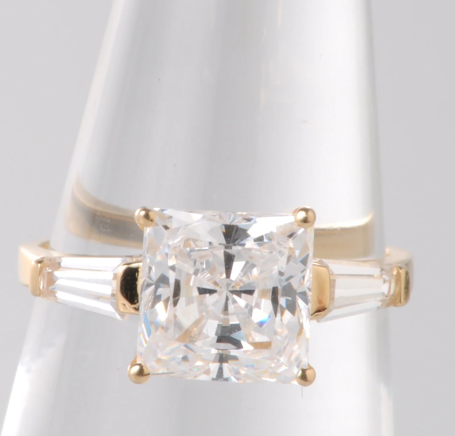 14k yellow gold featuring a princess cut cubic zirconia center stone flanked by two cubic zirconia accents. Contains 2.45 grams of 14k yellow gold.