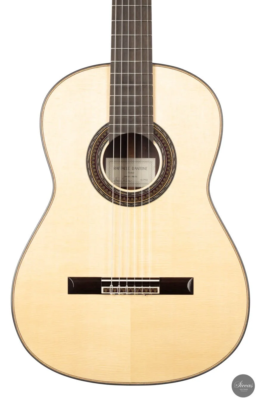 An acoustic guitar with a cream-colored body and dark fretboard, displaying the brand 'Raffaele D'Antone' inside the soundhole.