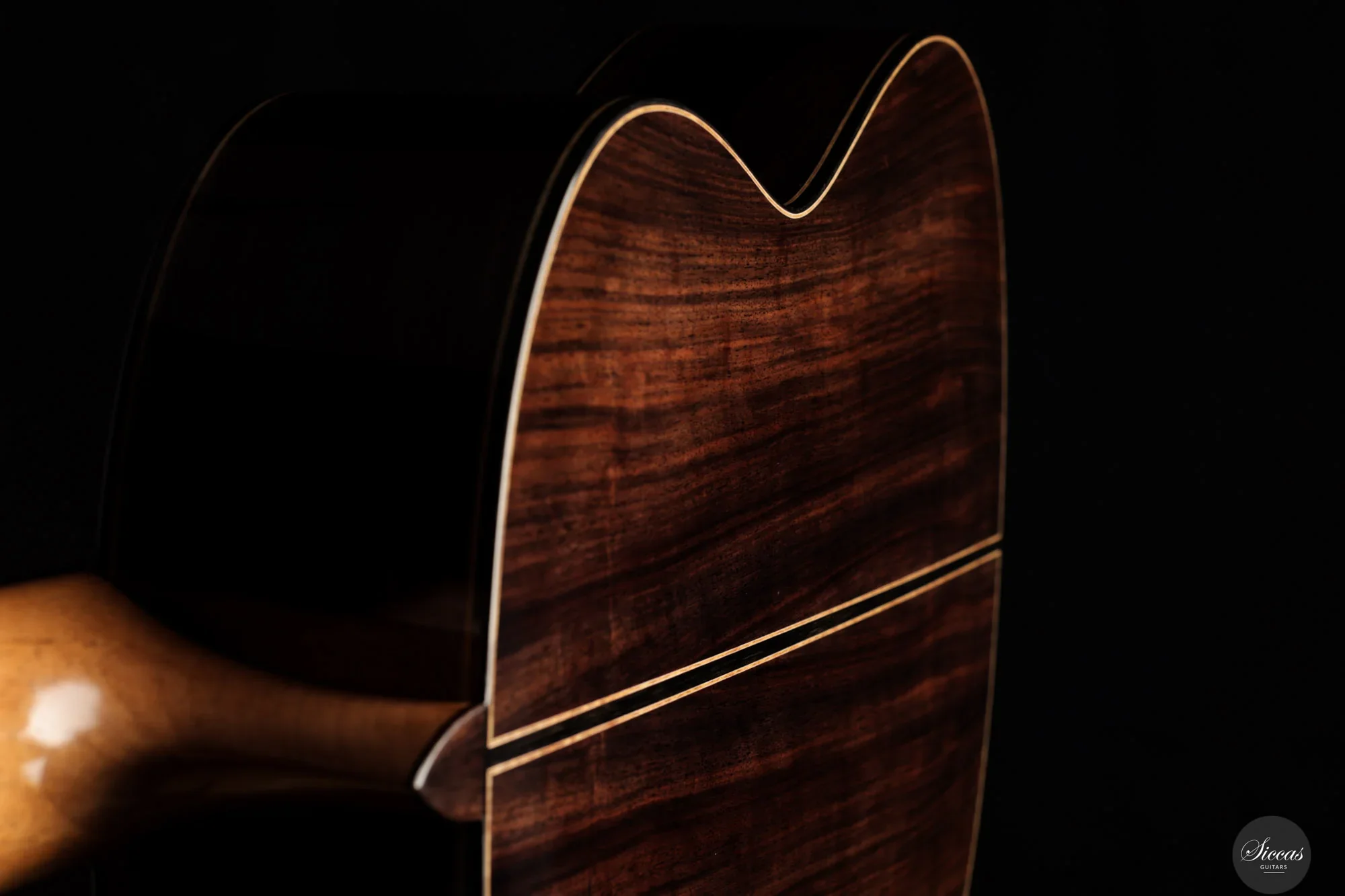 Close-up of a wooden acoustic guitar with a dark background.