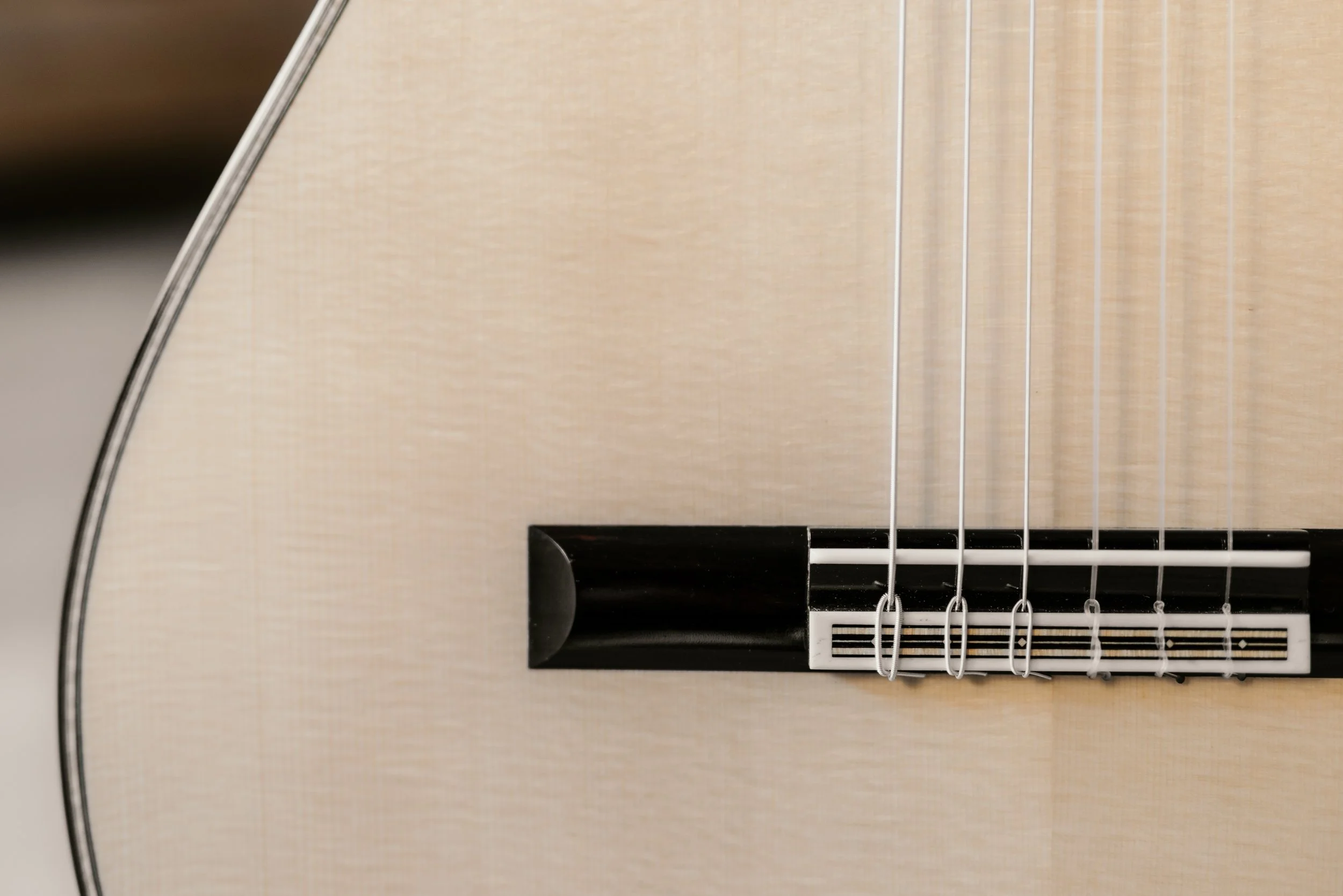 Close-up of an acoustic guitar's body, bridge, and strings.