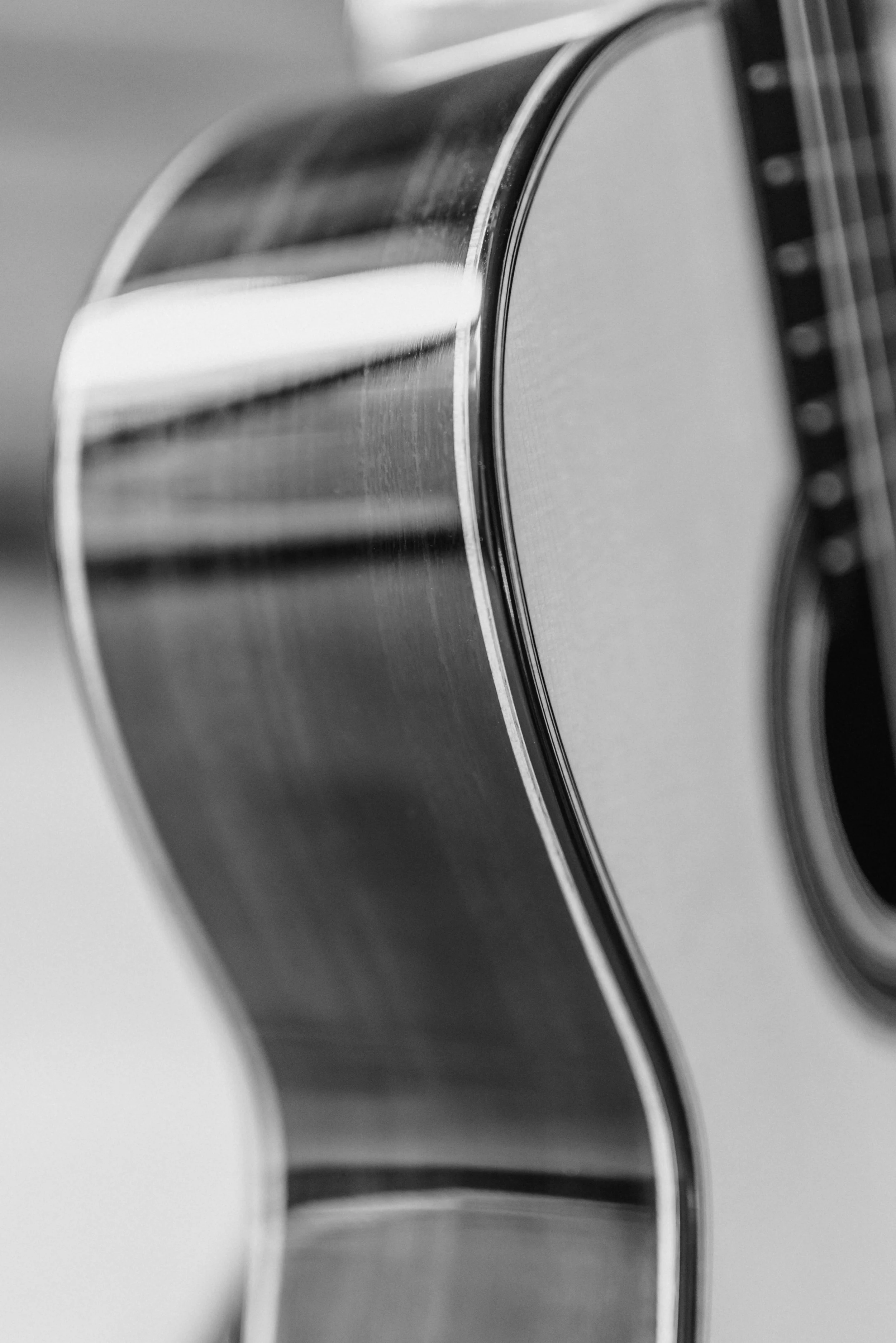 Close-up of the side of an acoustic guitar, showing the wooden body and sound hole.