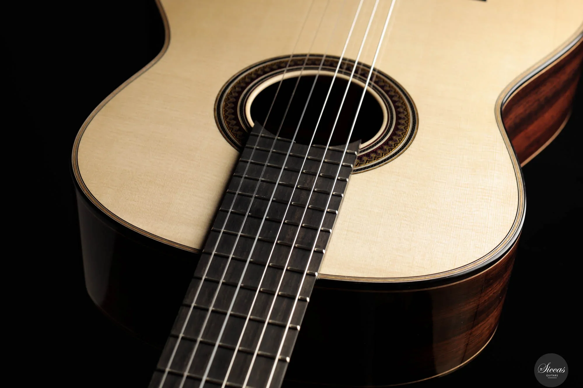 Close-up of an acoustic guitar with a light-colored top and dark fretboard.