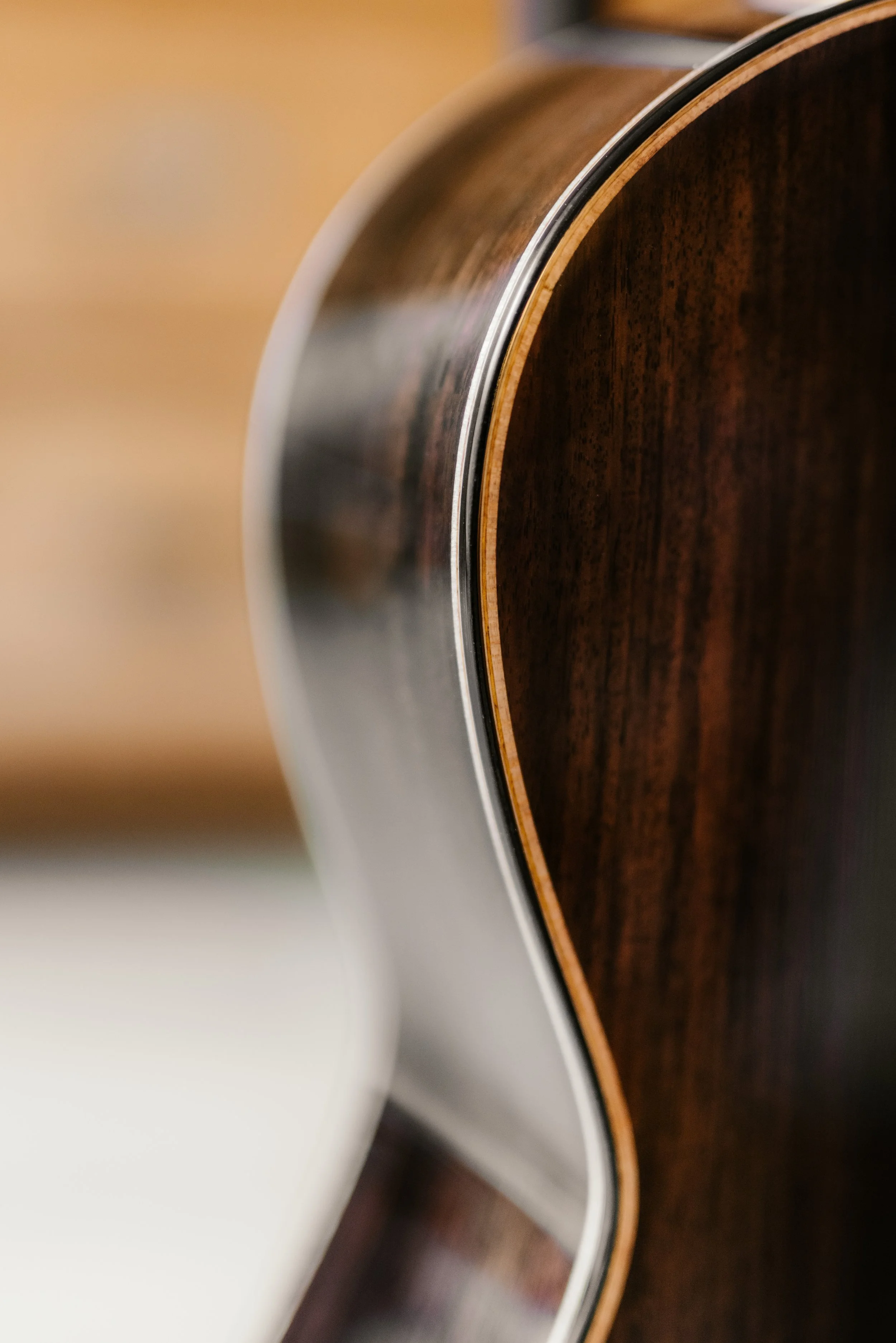 Close-up of the side and edge of an acoustic guitar showing the wood grain and binding.