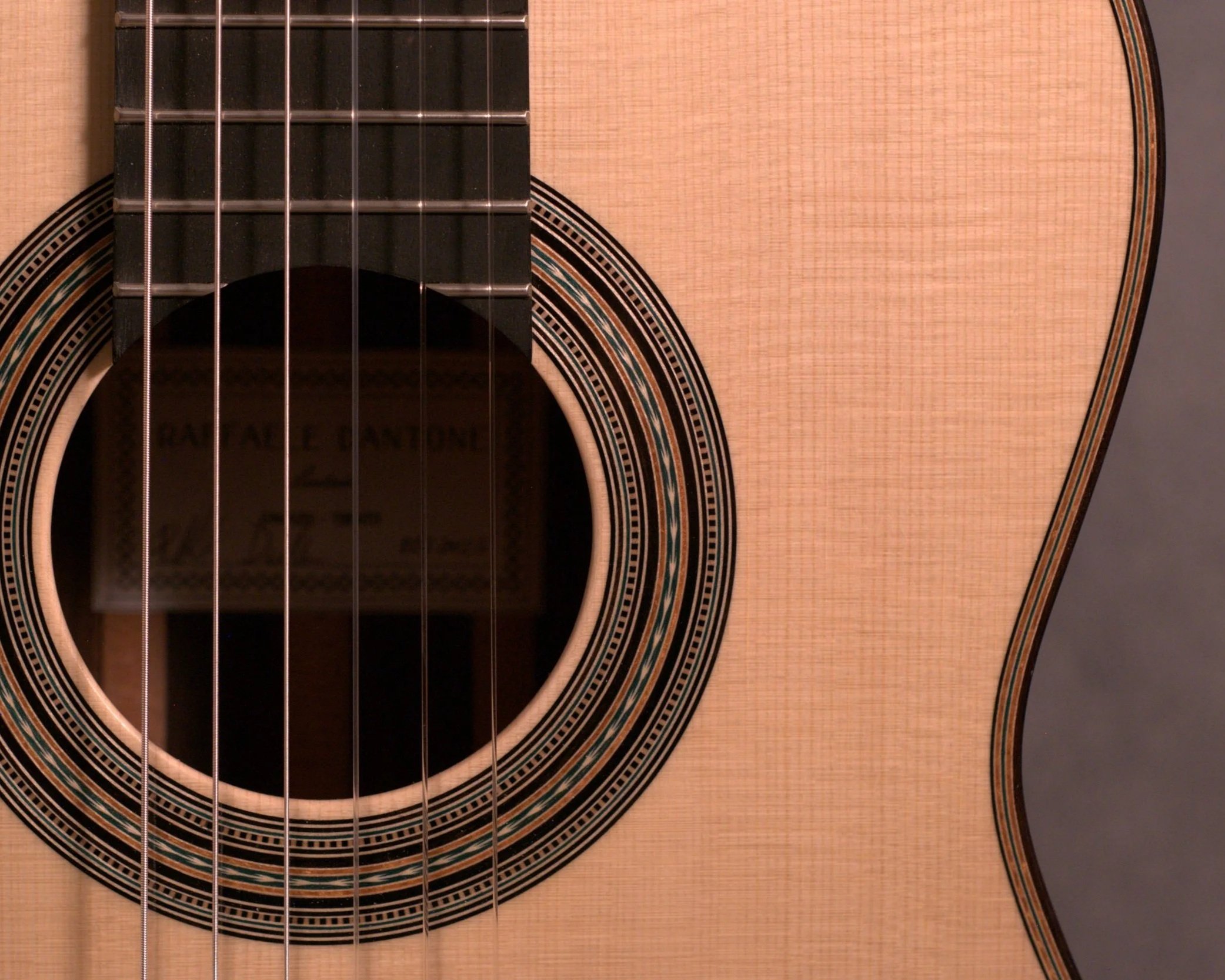 Close-up of an acoustic guitar showing the sound hole, strings, and part of the body with intricate rosette design.