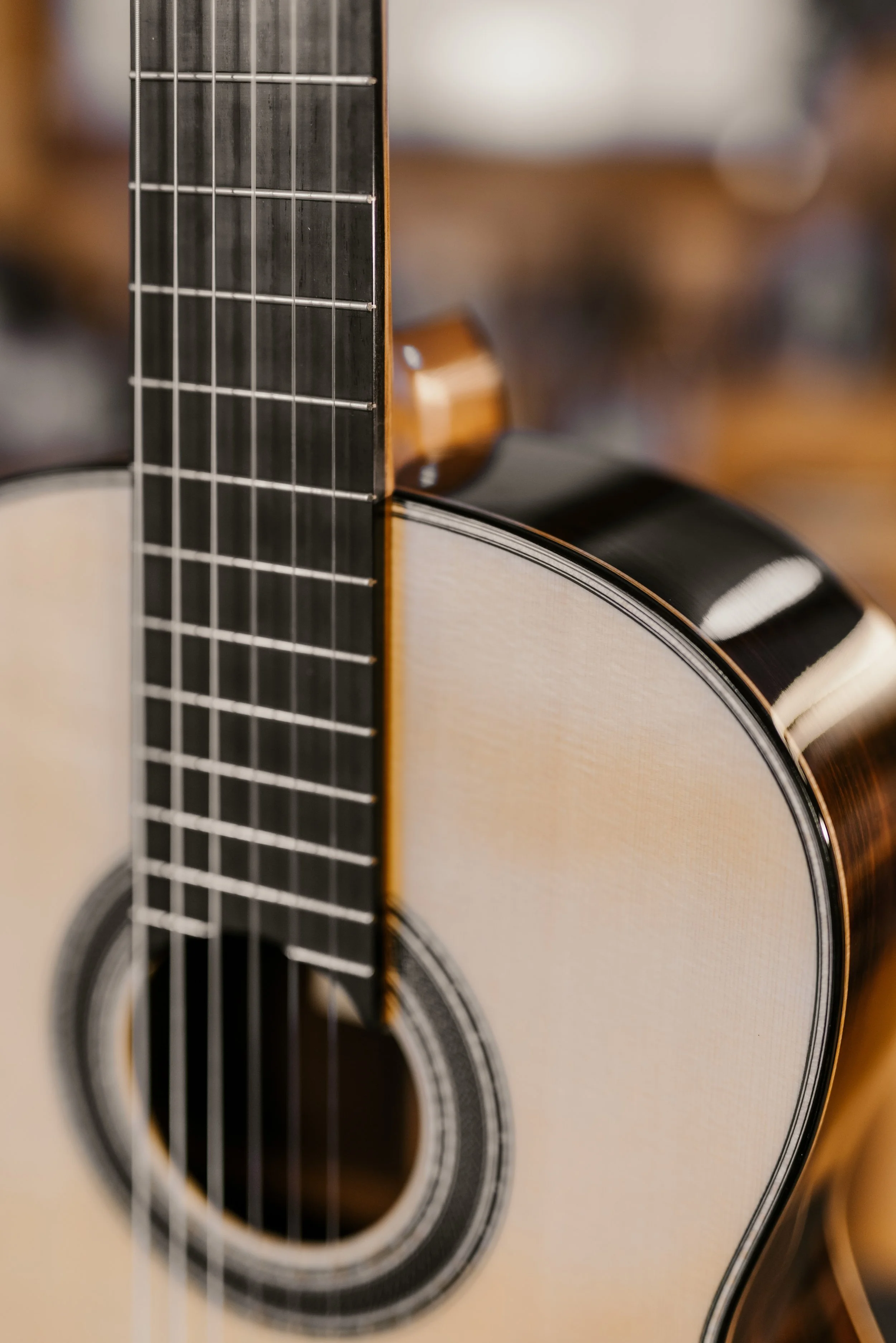 Close-up of an acoustic guitar showing the fretboard and body with a blurred background.