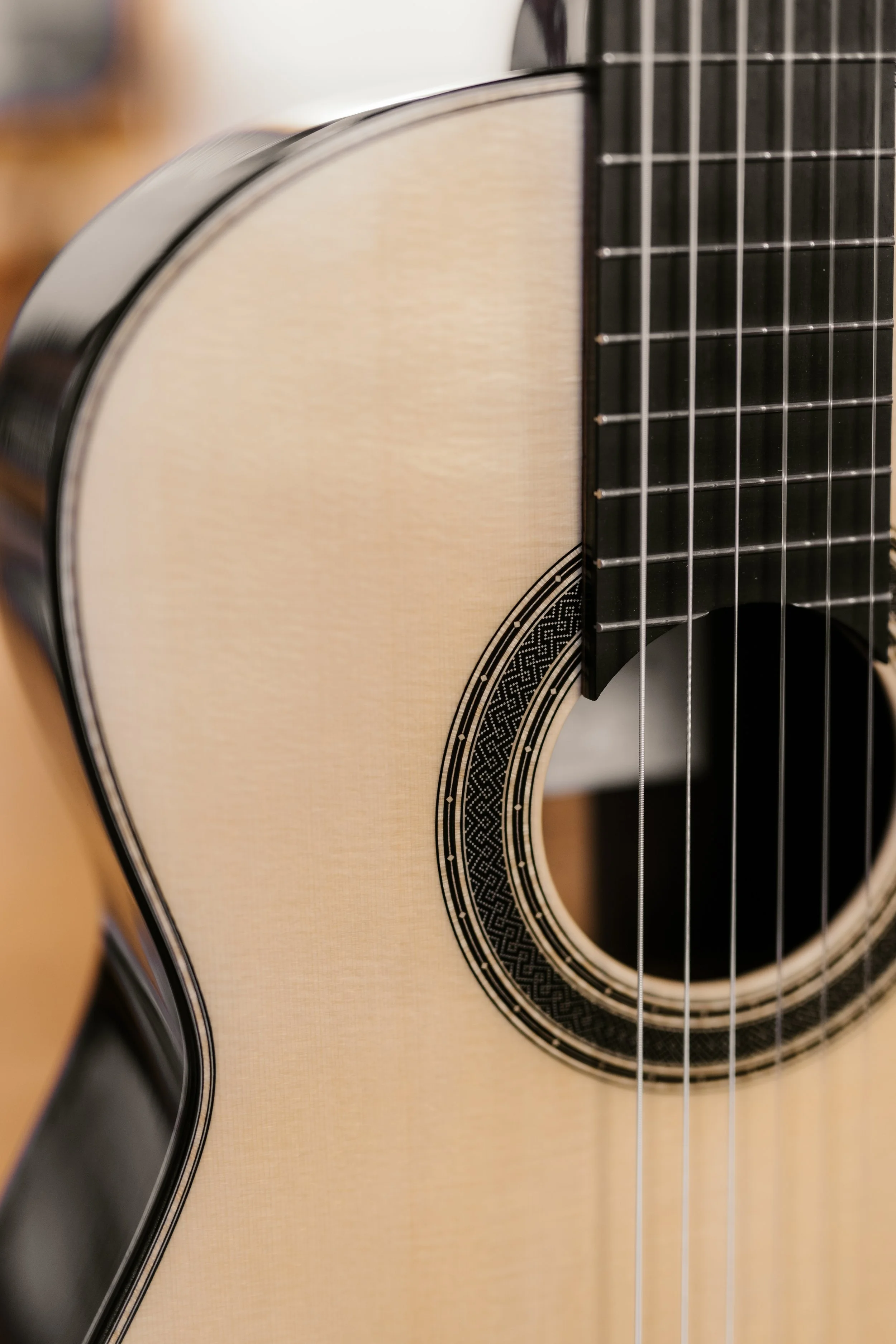 Close-up of a classical guitar's body, strings, and soundhole with intricate rosette design.