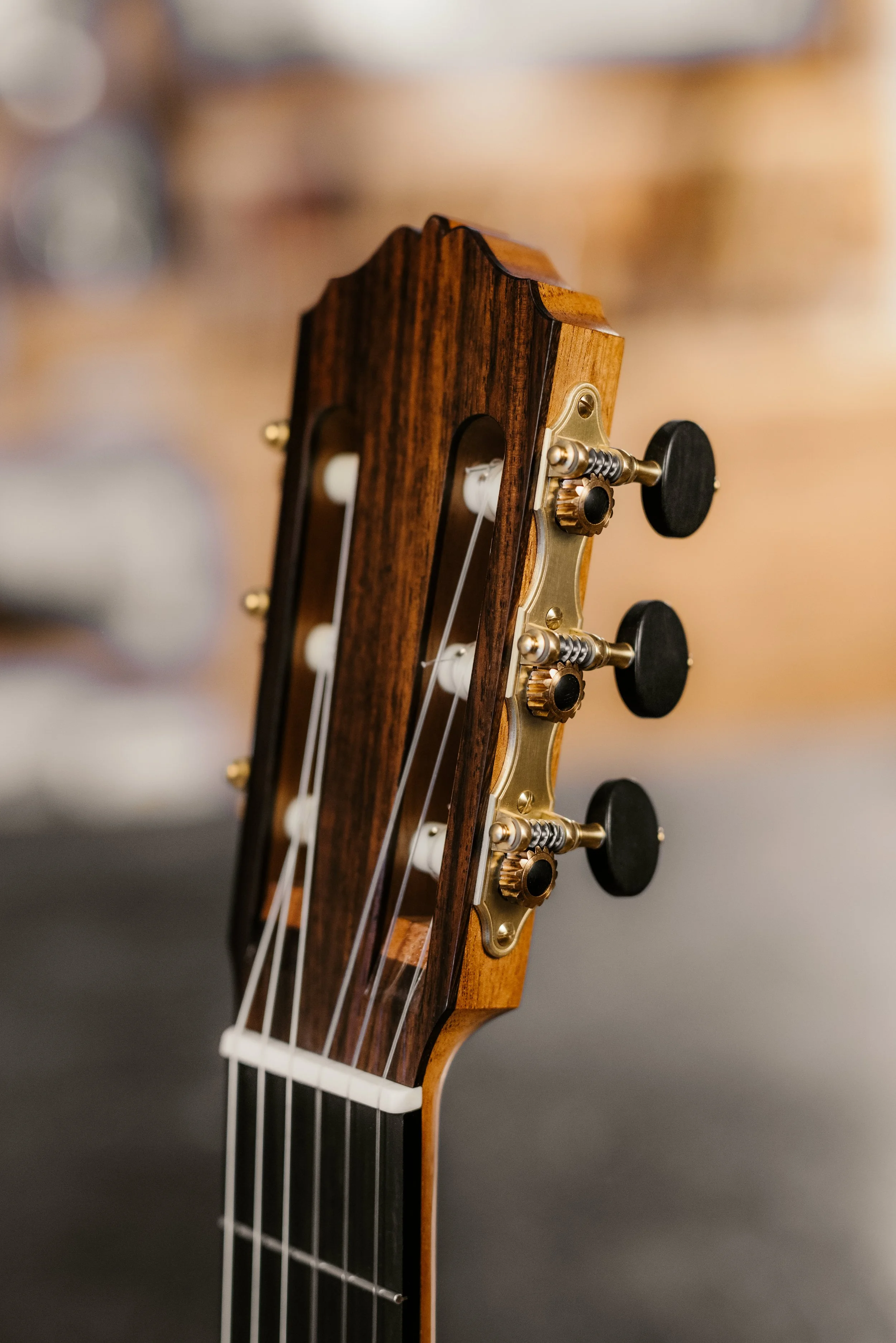 Close-up of the headstock of a classical guitar with tuning pegs and strings.