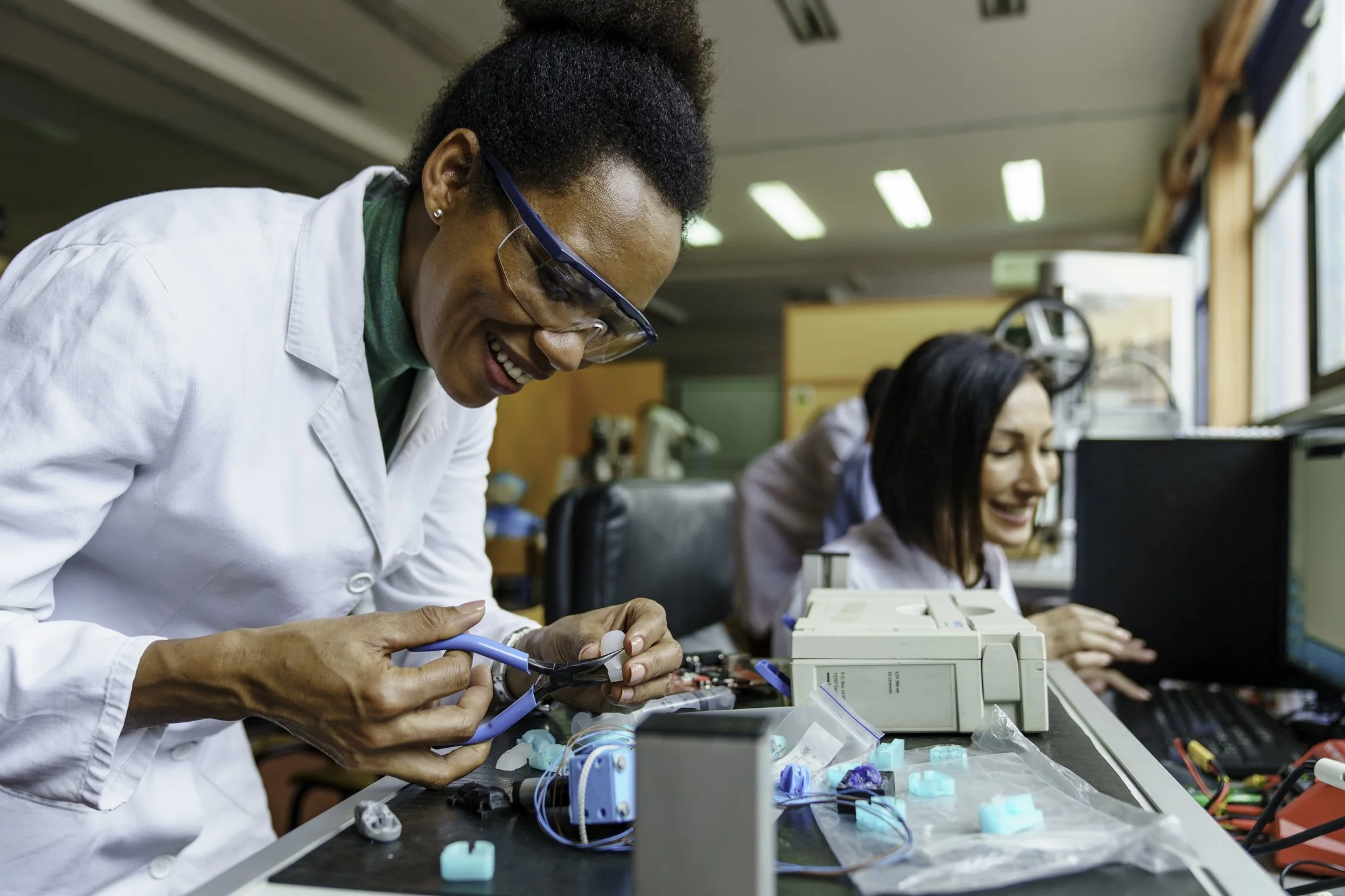Woman smiling working in a science lab with tools.