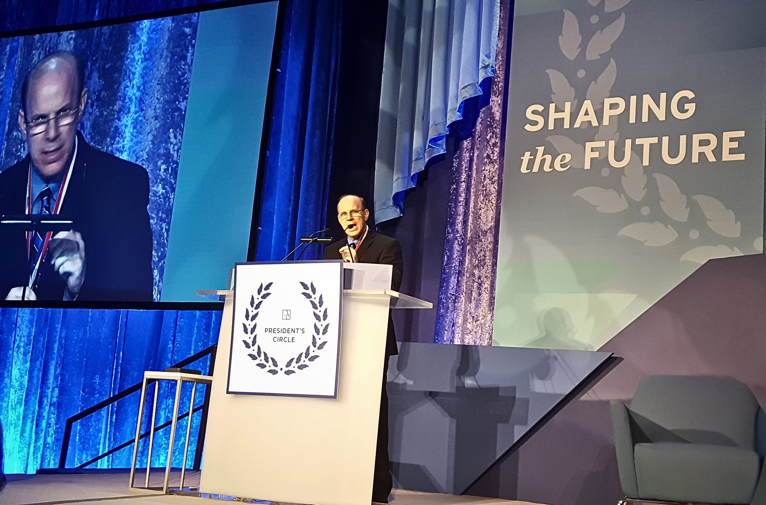 Dr. Mark Begel giving a speech on stage.