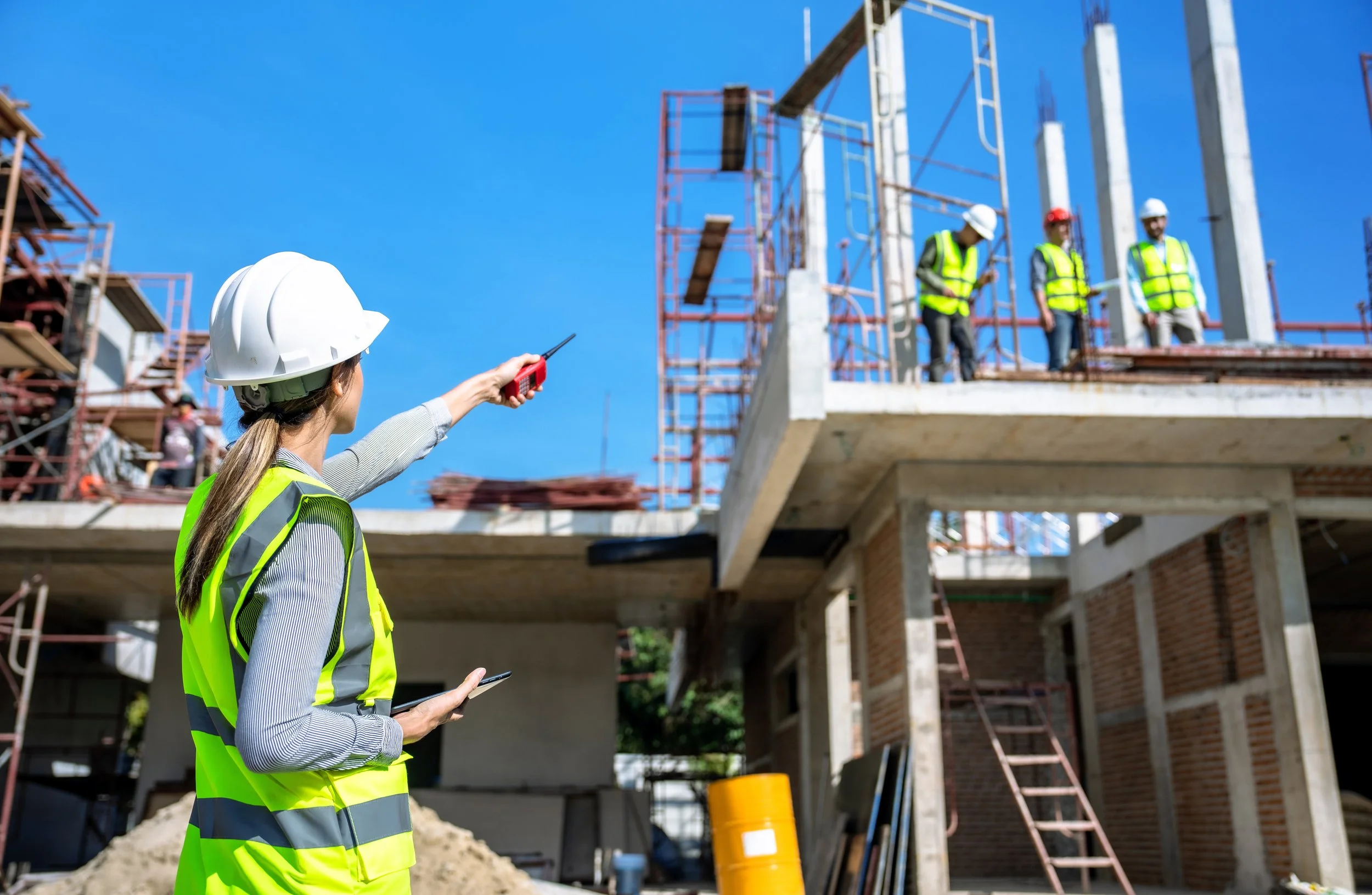 The female engineer talks to the contractors on the buildings roof.
