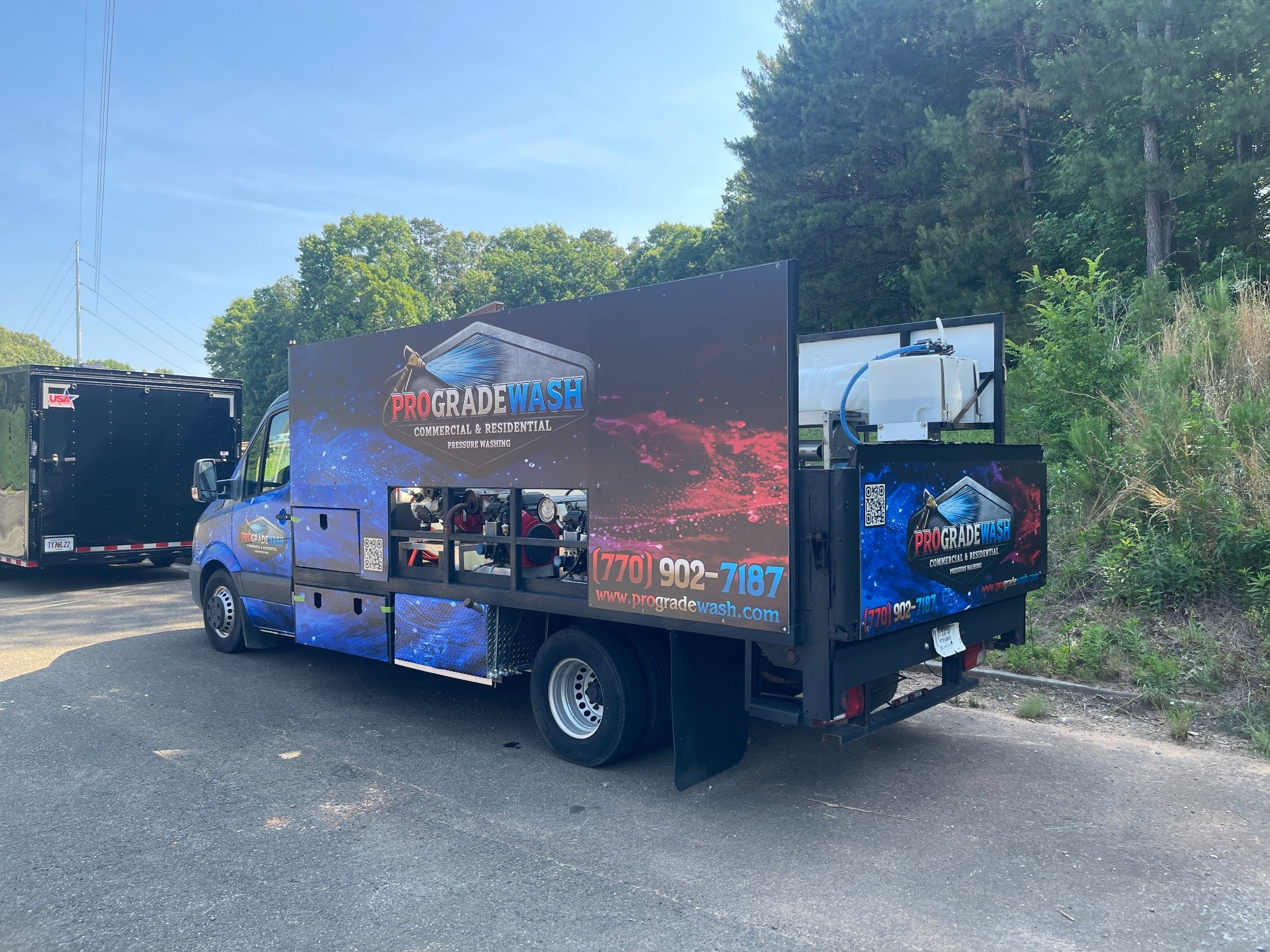 ProGrade Wash pressure washing truck and equipment trailer parked beside a road