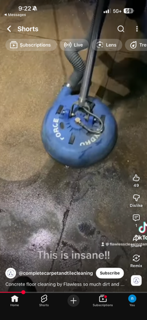 A blue floor cleaning machine on a concrete floor, with soil or dirt being cleaned on the ground, in a dimly lit room.