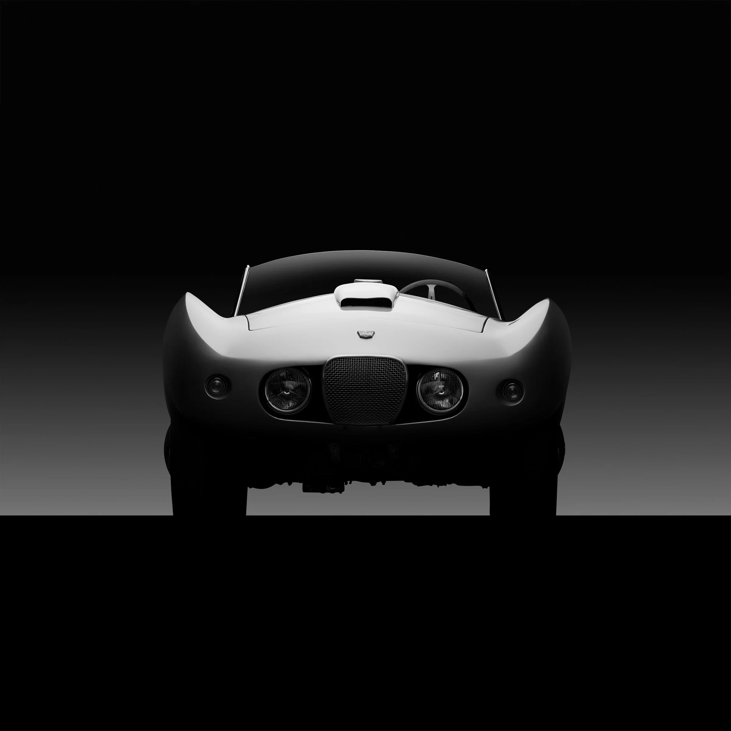 Quiet Curve by Bill Pack — a frontal automotive study distilled through hand-controlled illumination, emphasizing symmetry, tension, and sculptural stillness.