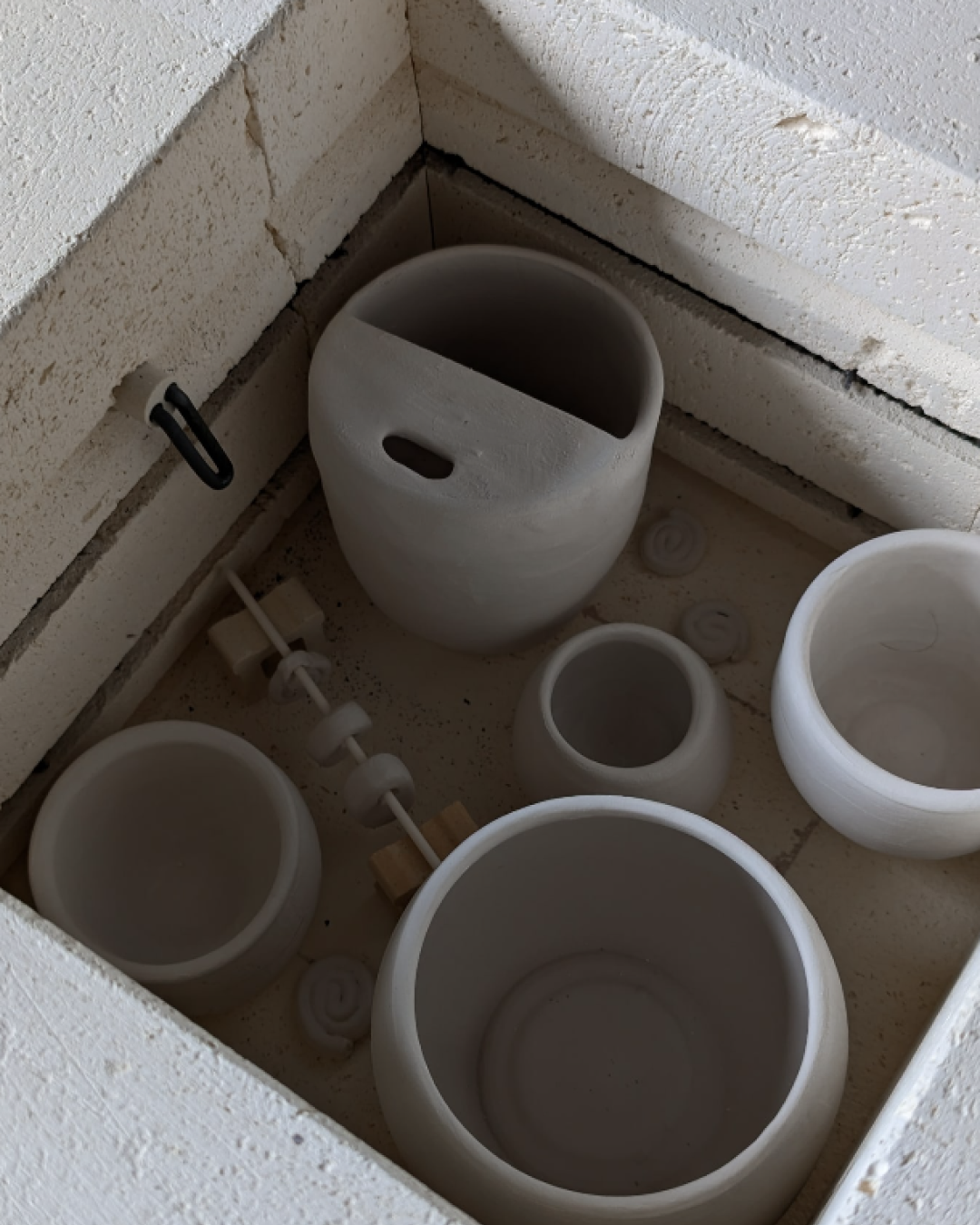 Various unglazed ceramic and pottery pieces in a box, including bowls and vases, with some block and wheel components.