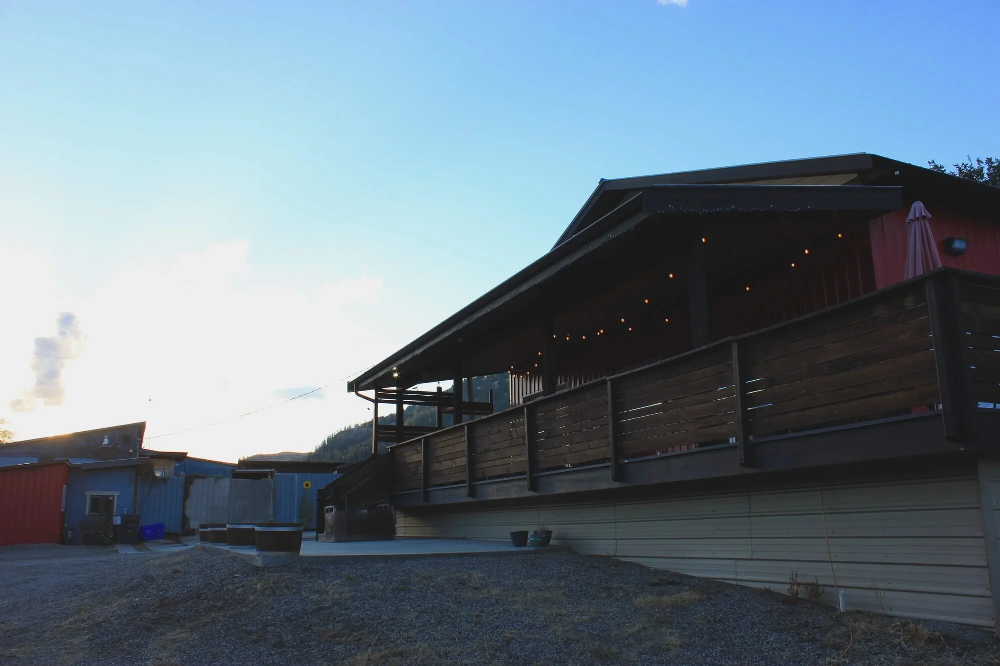 Tony's Craft Cidery with a large wooden deck and string lights, located in a mountainous area during dusk.