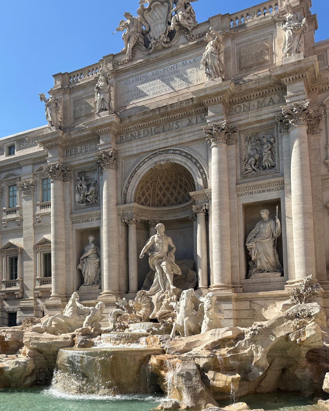 Trevi Fountain in Rome, Italy, with ornate statues and cascading water beneath a clear blue sky