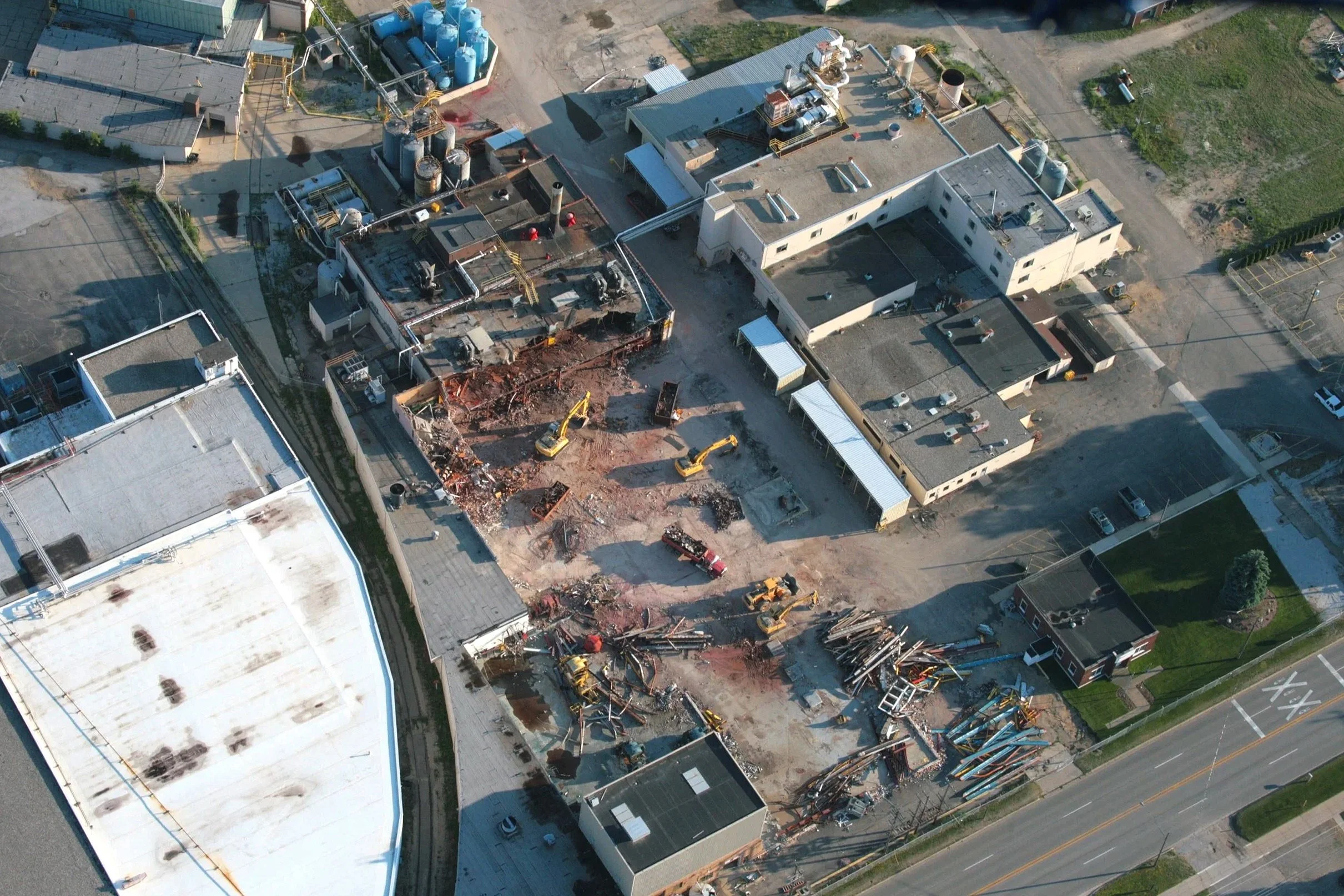 Aerial view of a construction site where a building is being partially demolished, with construction machinery and debris scattered around.