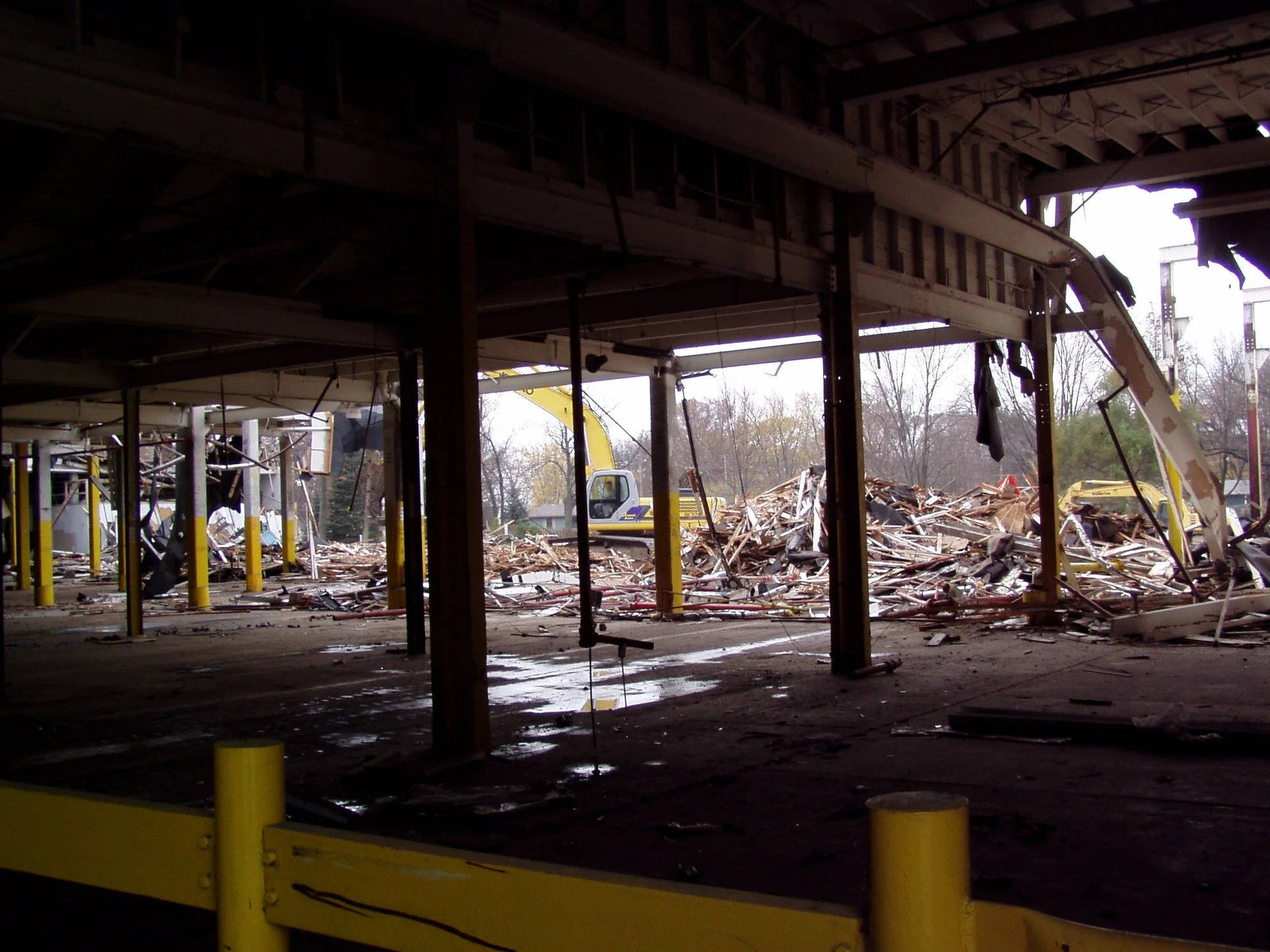 View of a demolished building with construction equipment and debris outside.