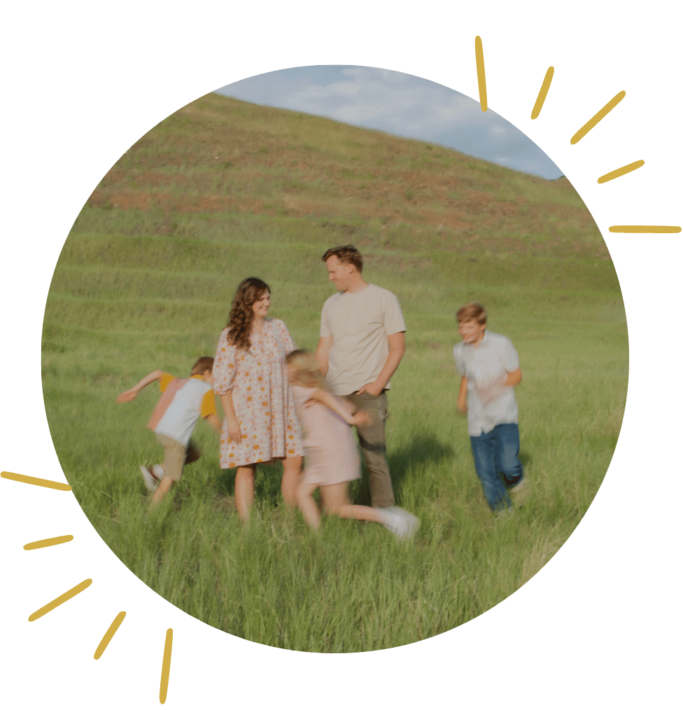 Family playing together in a grassy field under blue skies