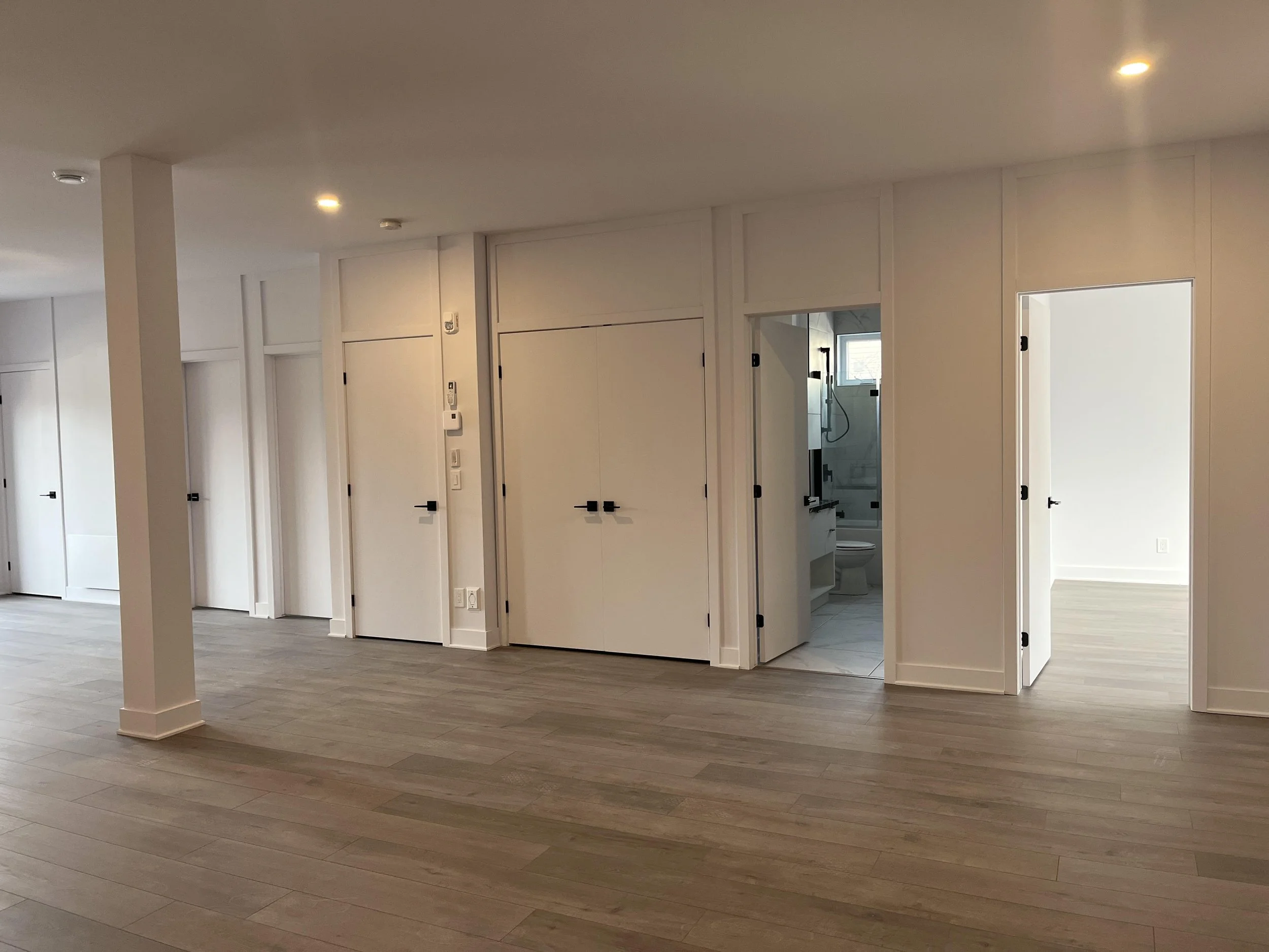Intérieur d'un appartement moderne avec plusieurs portes blanches et un sol en bois clair.