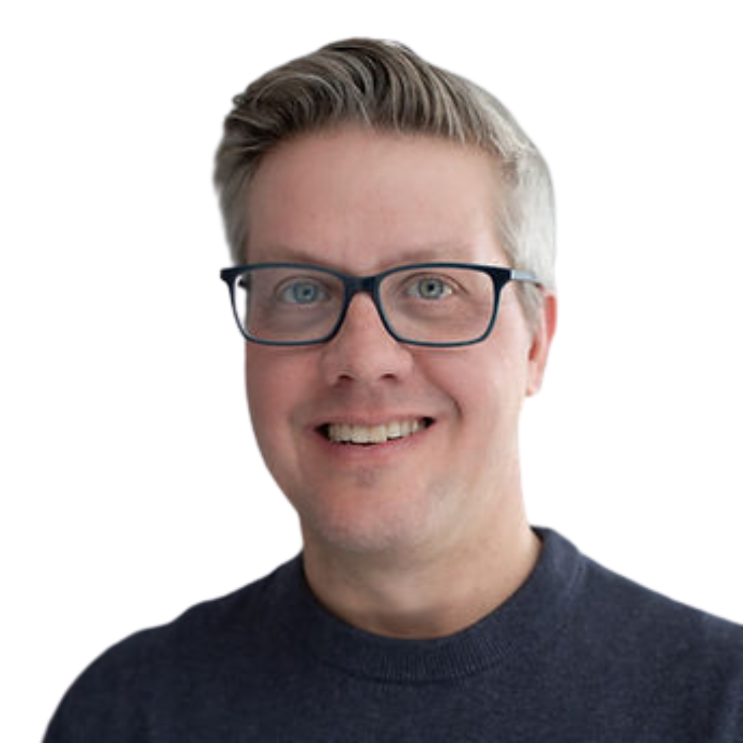 A smiling man with glasses and gray hair wearing a navy blue shirt.