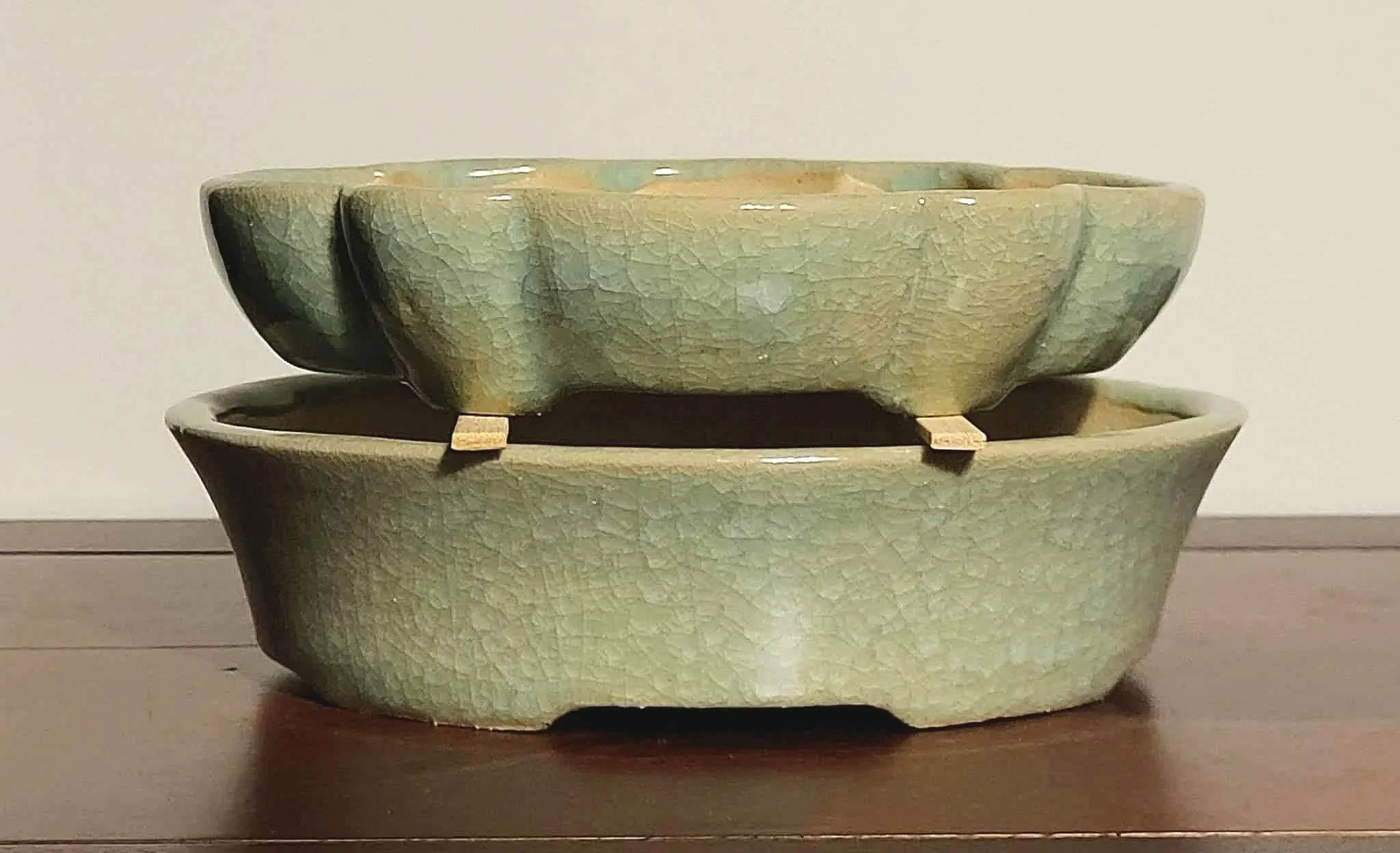 Two stacked ceramic bowls, one on top of the other, placed on a wooden surface, with a plain background.