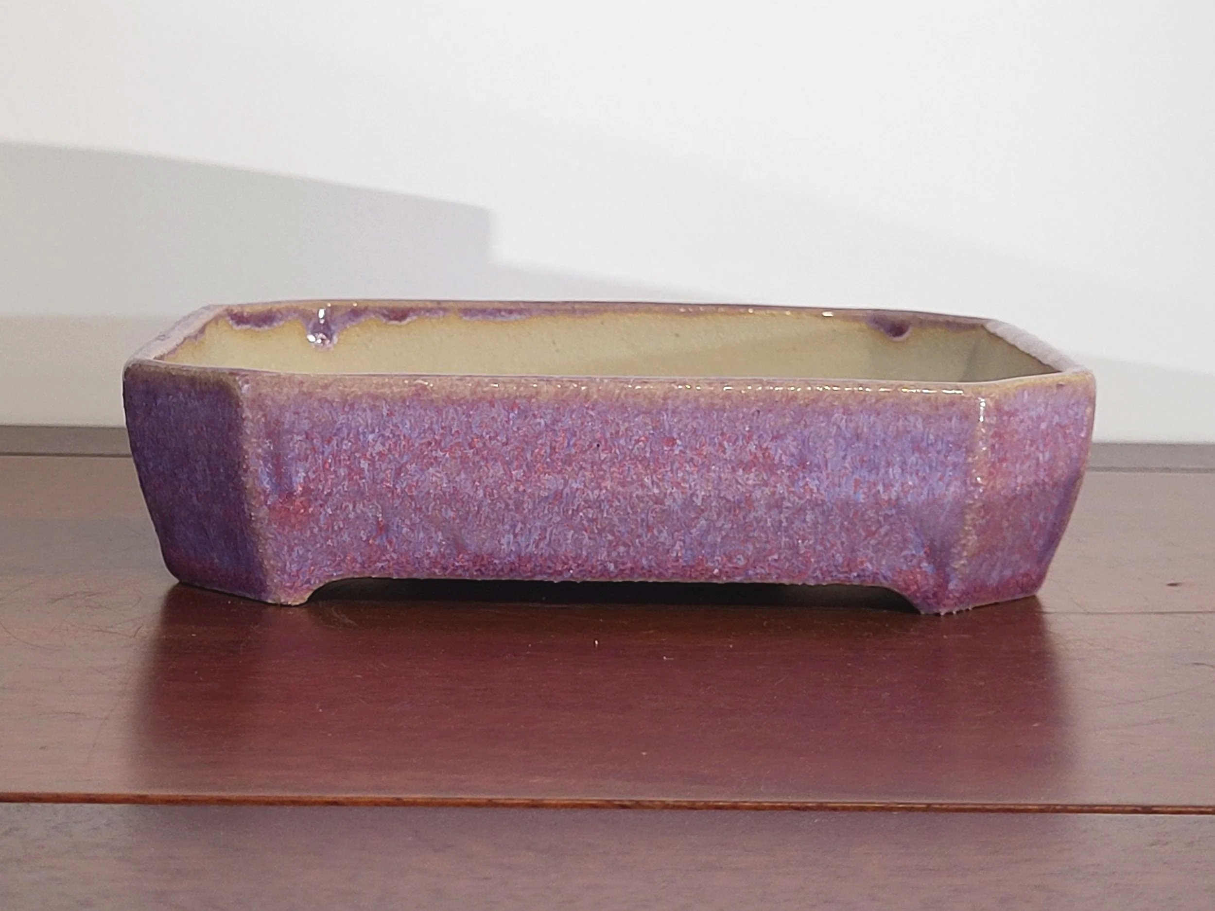 Rectangular ceramic planter with purple and pink glaze sitting on a wooden surface.