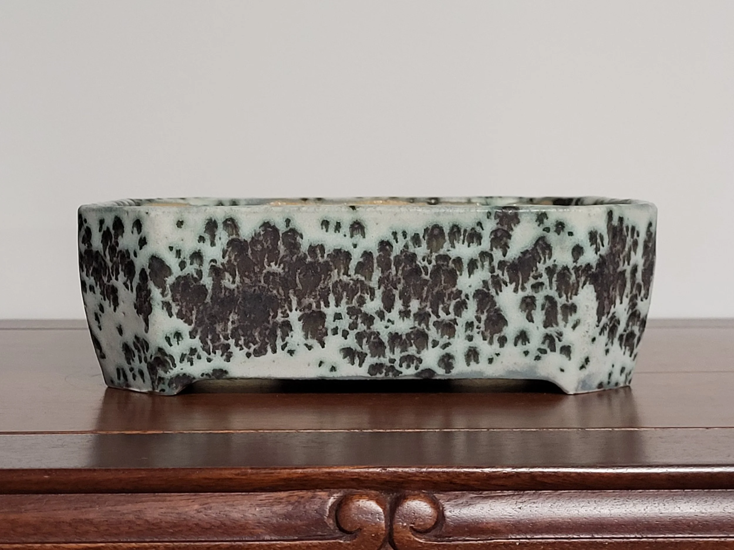 A rectangular ceramic dish with a black and white speckled pattern, sitting on a wooden surface.