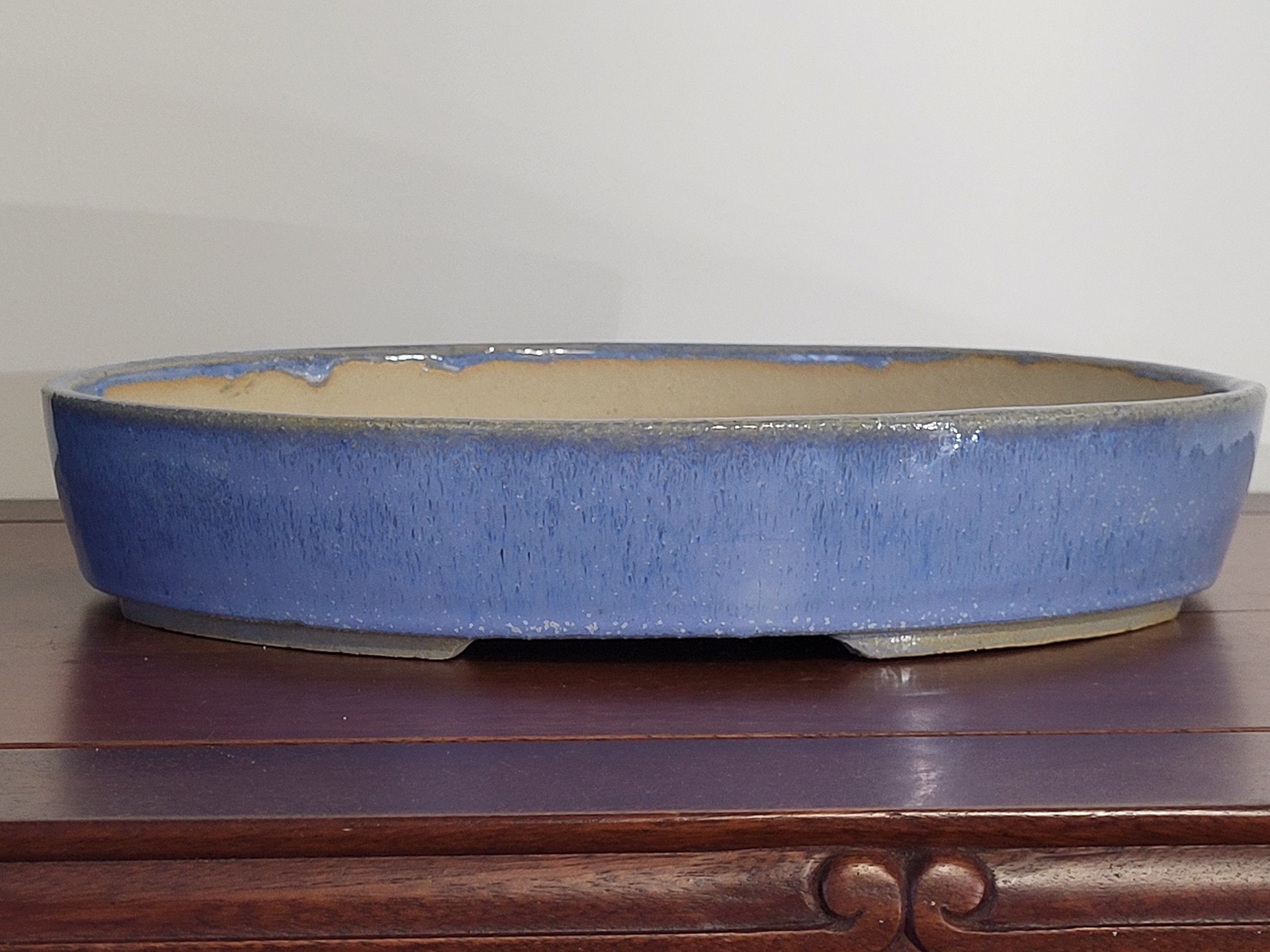 A blue ceramic oval-shaped planter bowl with a glazed finish, sitting on a wooden surface. The interior appears unfinished or lightly glazed.