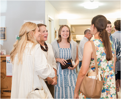 Group of women in conversation indoors, smiling and laughing.
