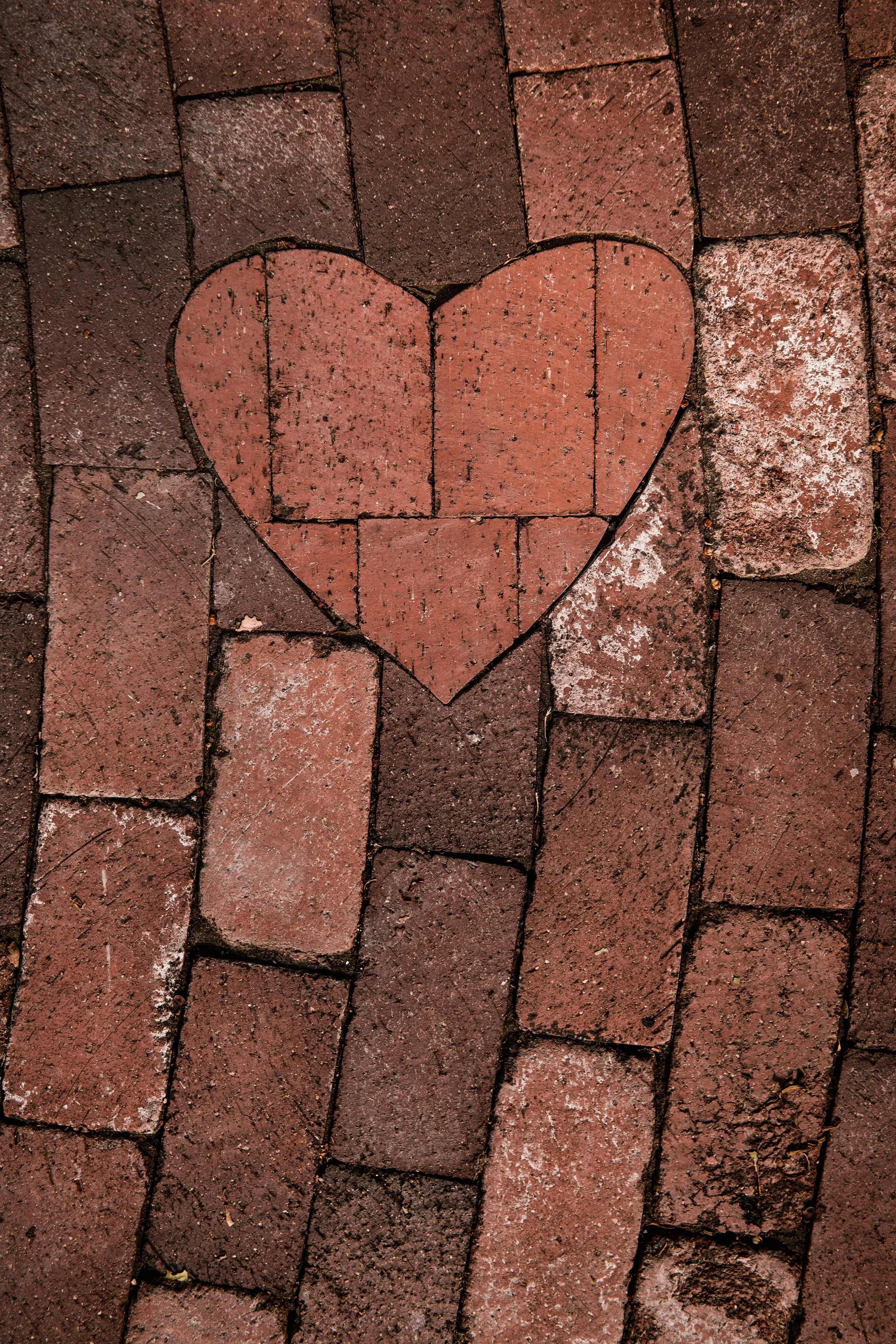 Red brick pavement with a heart shape painted on the bricks.