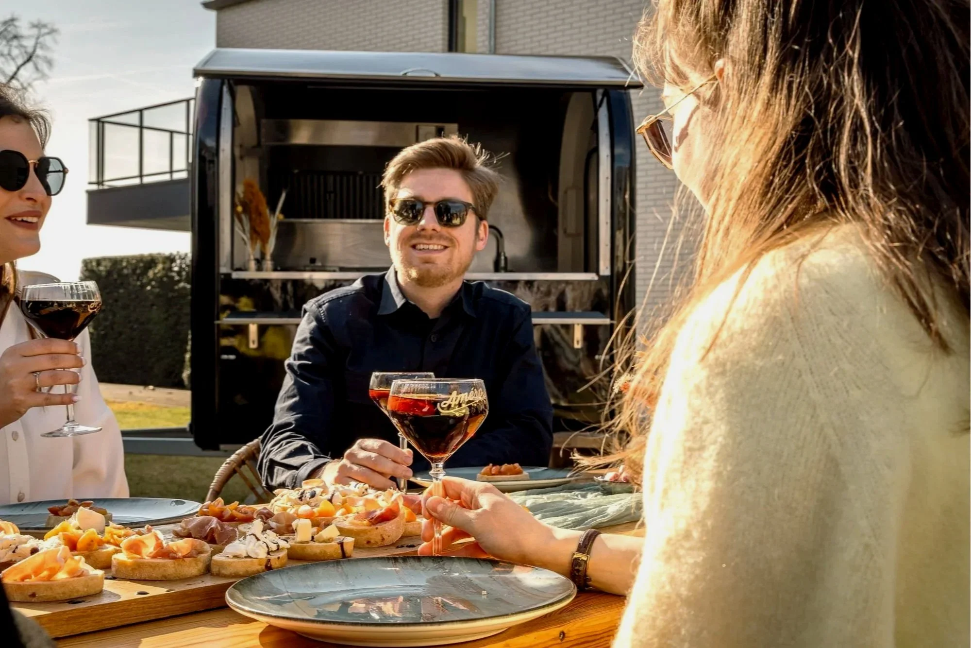 Vrienden genieten van wijn en hapjes buiten voor een foodtruck.