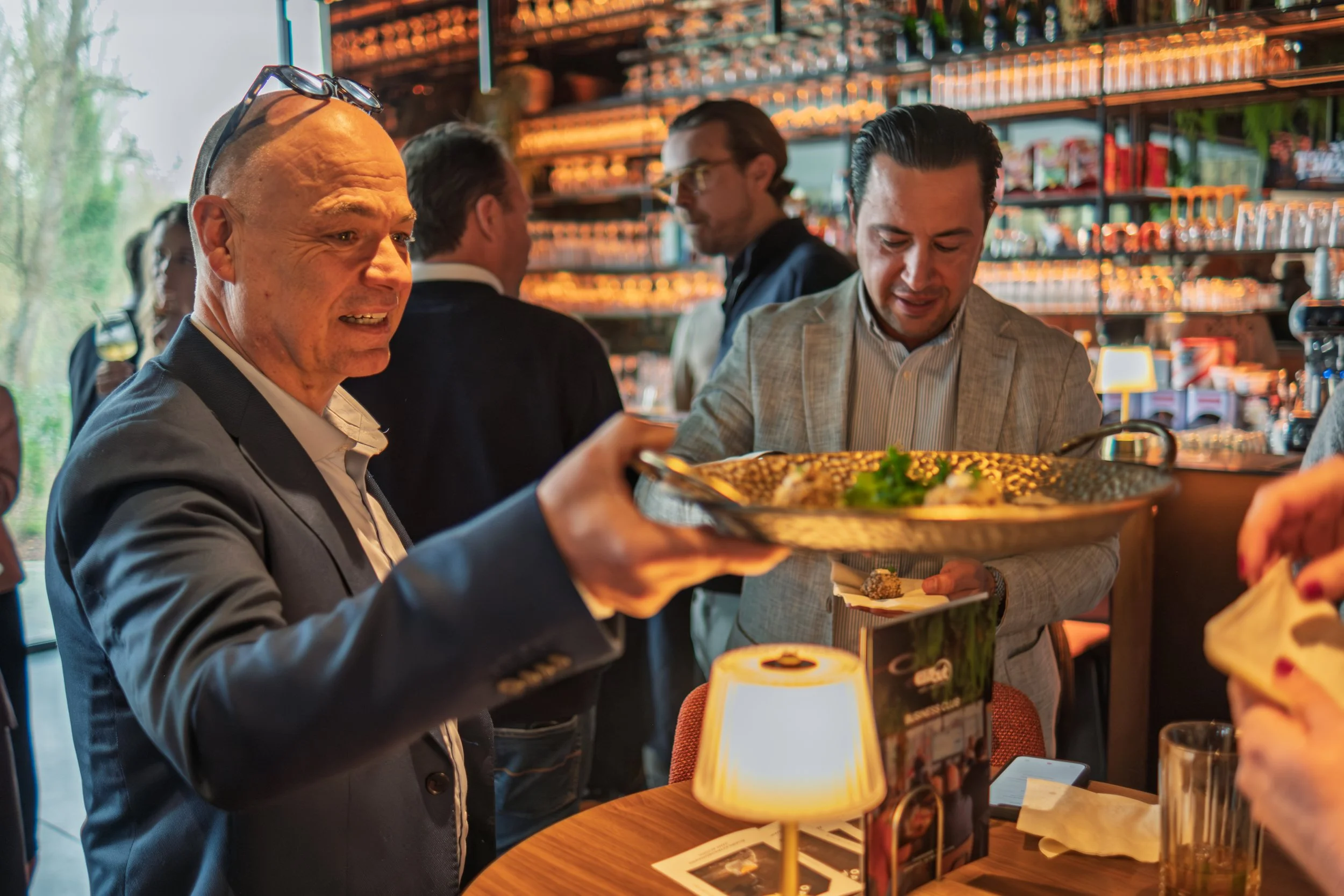 Man in een restaurant of bar die een gerecht serveert aan een andere man.