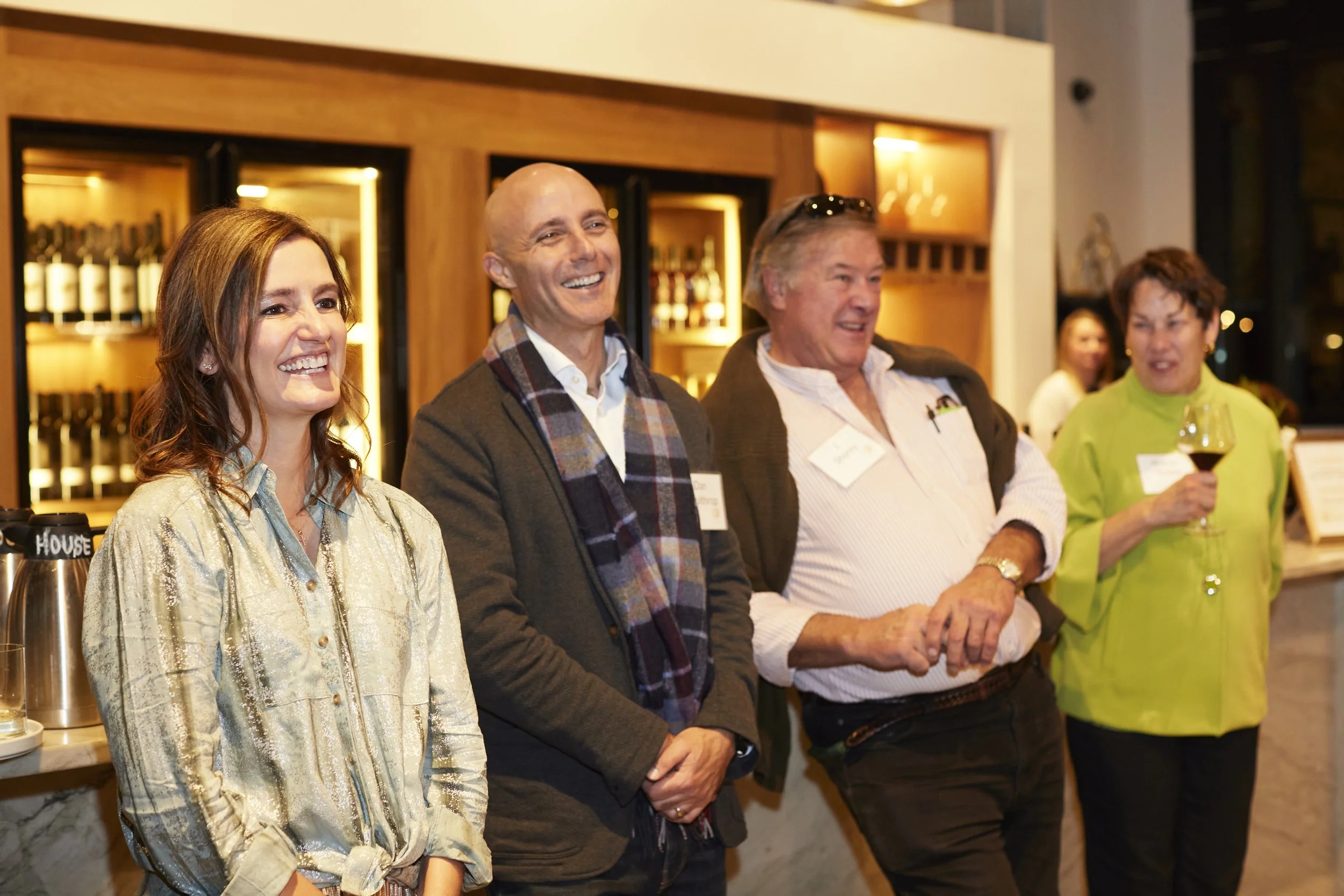 Four people smiling during a speech at an event