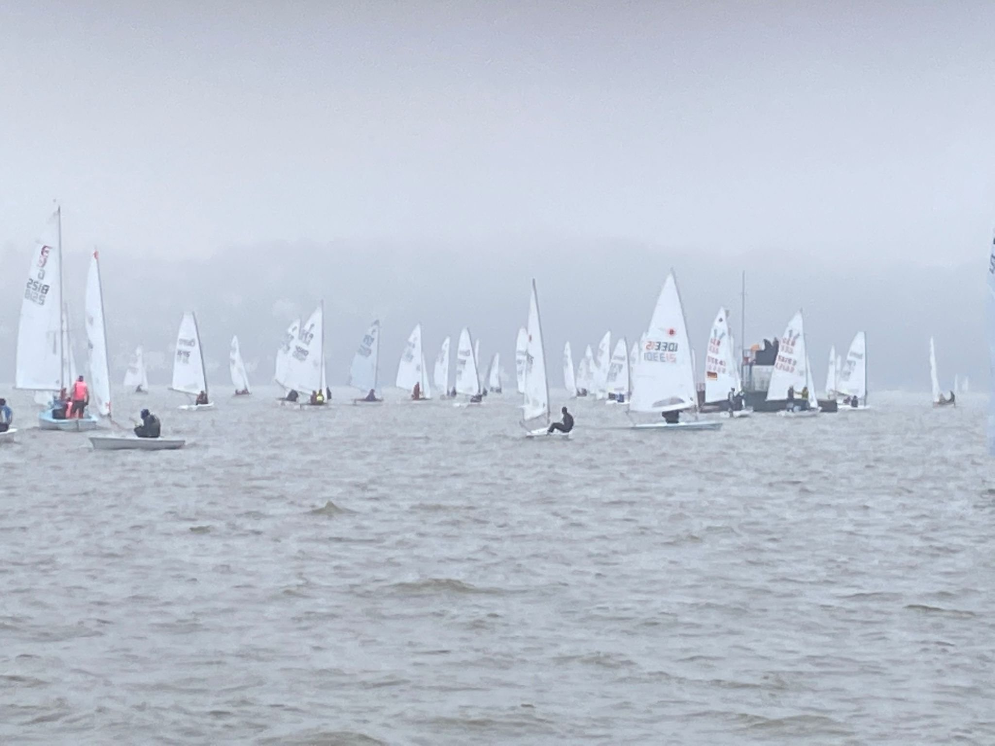 Mehrere kleine Segelboote auf dem Wasser bei bewölktem Himmel.
