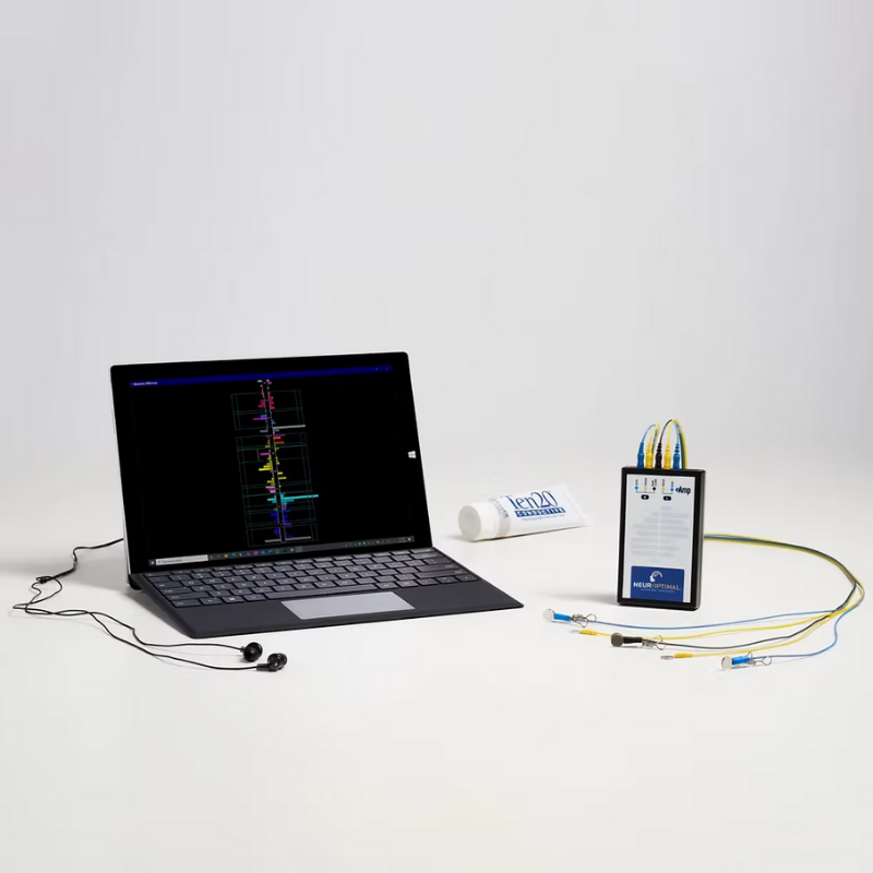 A laptop displaying a brainwave analysis, a pair of ear headphones, and a medical device with multiple wires and electrodes connected to it.