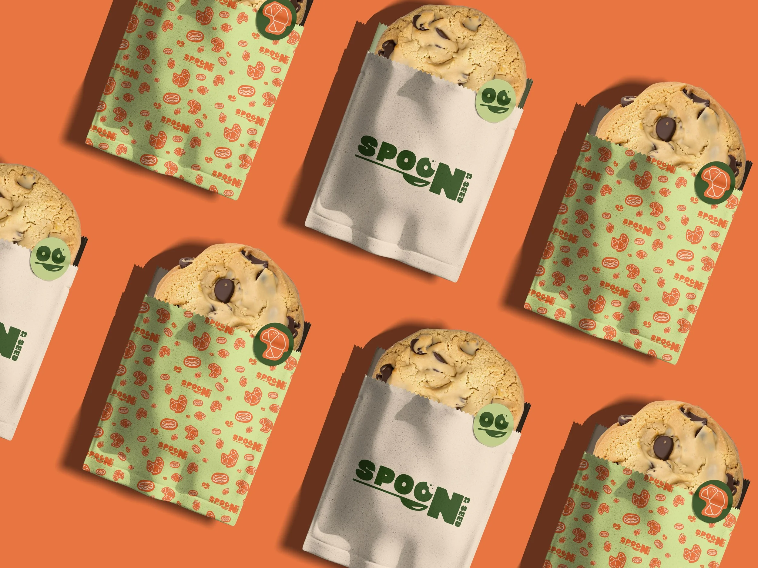 Multiple cookies in green and white paper wrappers labeled 'Spoon' with orange-patterned design, arranged on an orange background.