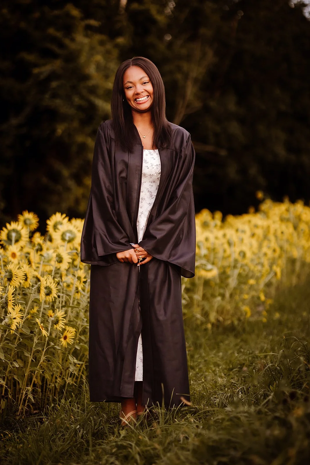 Senior portrait in sunflower field with cap and gown. 